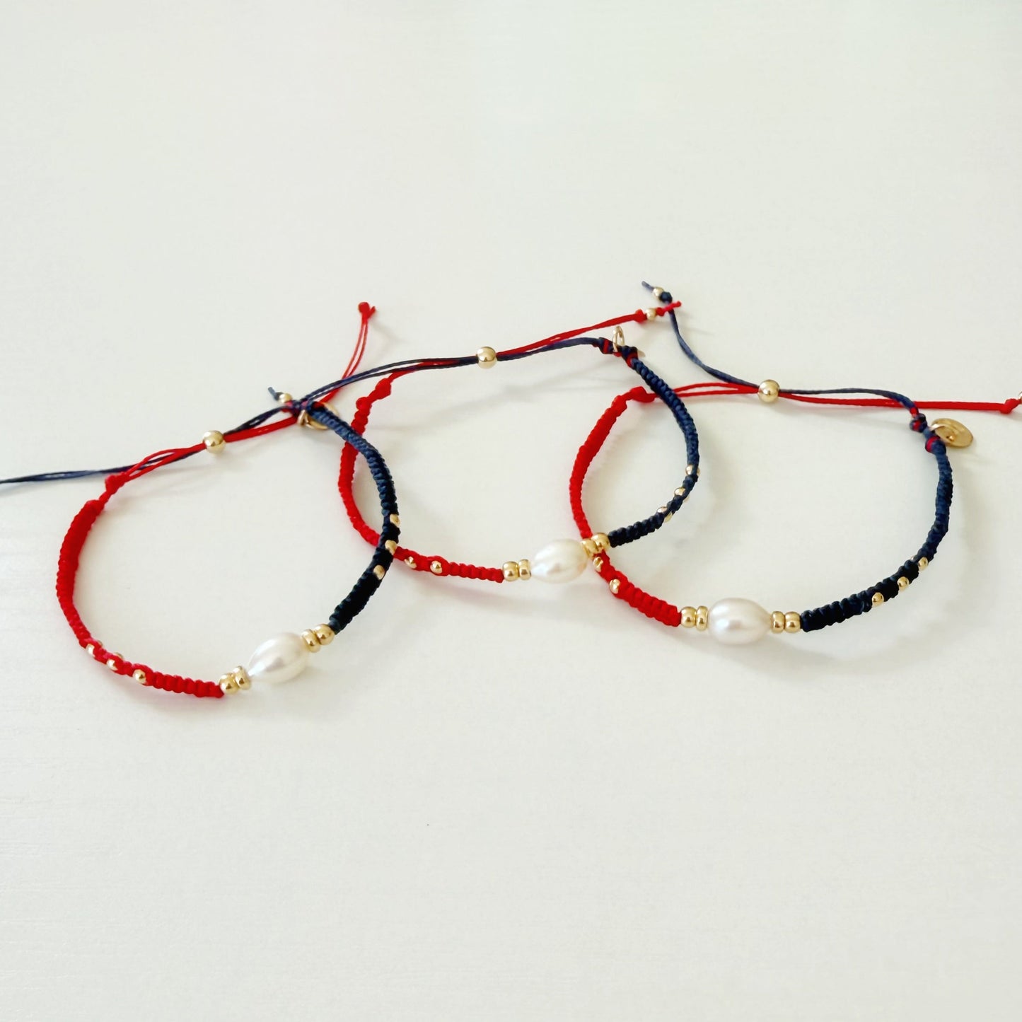 Three beaded bracelets in red, white, and blue on a white surface