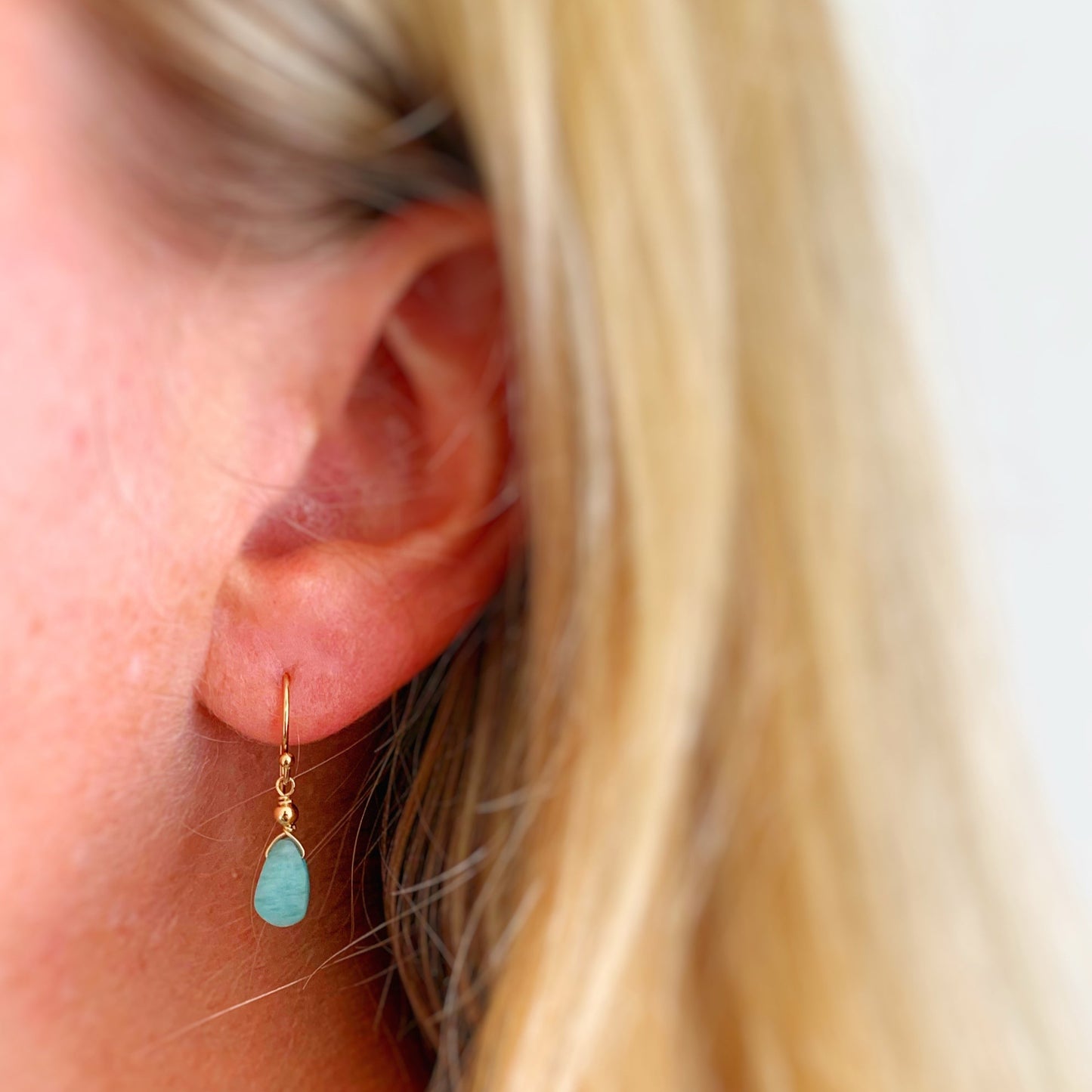 The captiva earring by mermaids and madeleines is a small faceted briolette of amazonite suspended from 14k gold filled earring wires. It's a very dainty drop. This earring is pictured on an earlob for size reference.