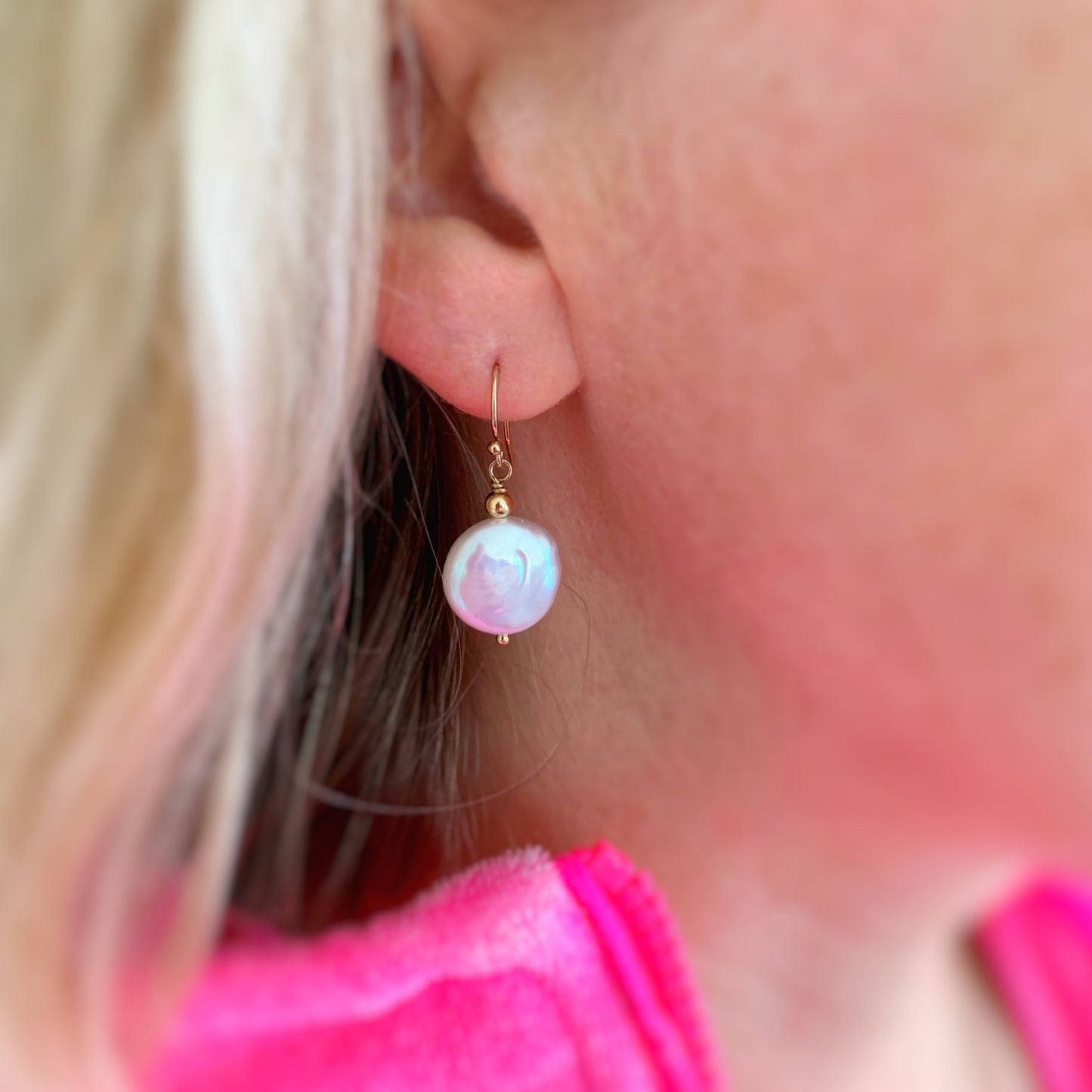 the newport earrings created by mermaids and madeleines are freshwater coin pearls with 14k gold filled findings and ear wires. These are simple and classic dangle earrings and this is a photograph close up of a newport earring on an ear lobe