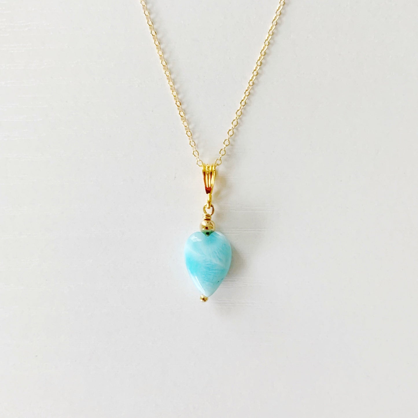 the ocean lover by mermaids and madeleines is a pendant style necklace with 14k gold filled chain and findings and an aqua larimar heart drop. this necklace is photographed close up on a white surface