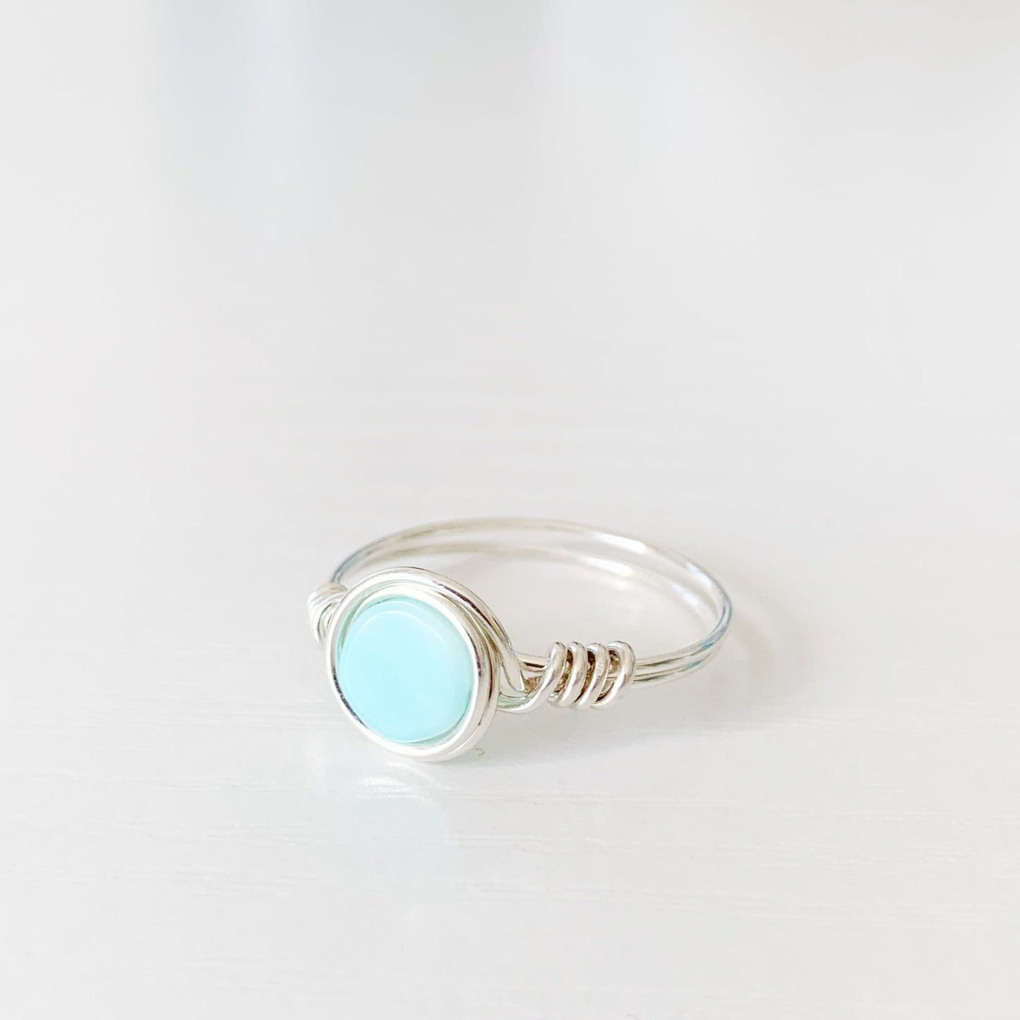 the island hopper ring by mermaids and madeleines is a sterling silver wire-wrapped style ring with a Peruvian opal coin bead at the center. this ring is photographed from the front on a white surface