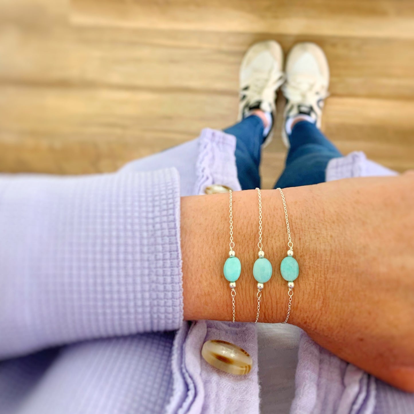 the mermaids and madeleines laguna bracelet is an adjustable style with sterling silver chain. The bracelet has an aqua amazonite oval bead at the center with a sterling silver slide bead at the clasp to make it adjust. this is a photograph of a wrist with 3 laguna bracelets on it