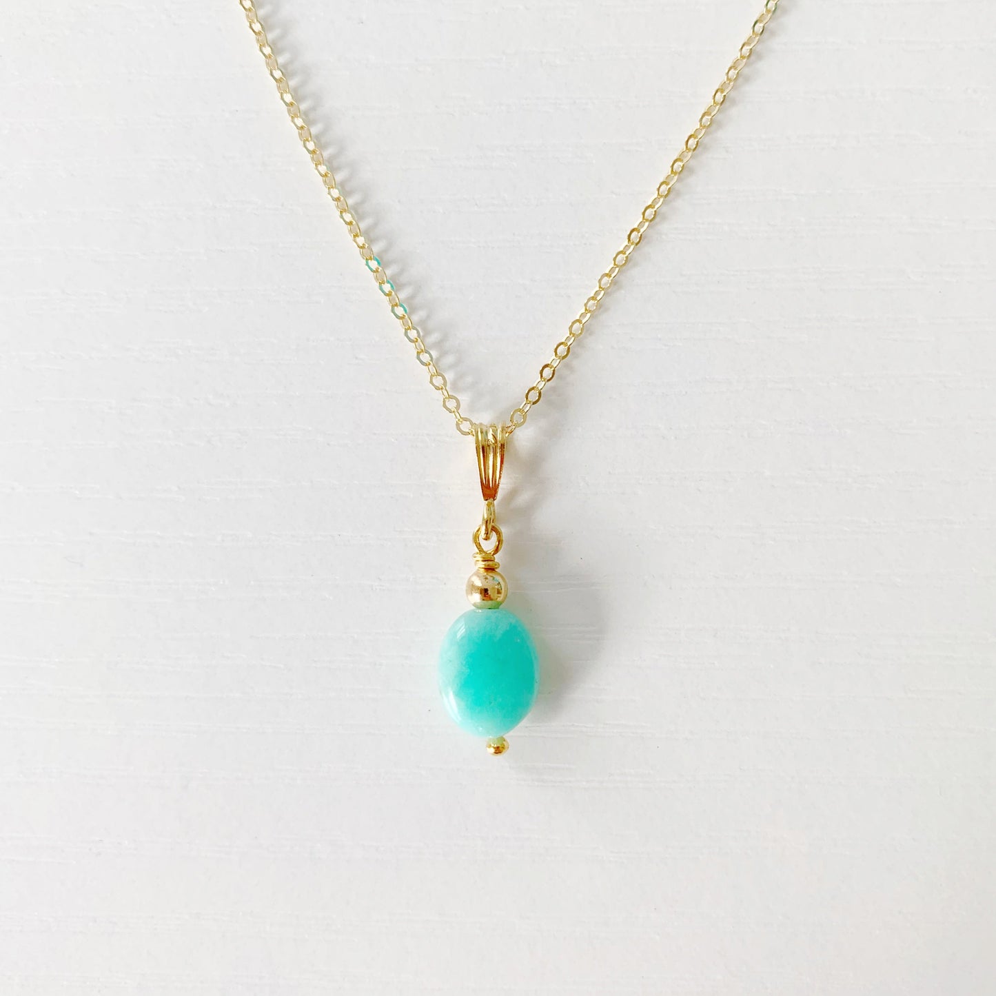 the mermaids and madeleines laguna necklace is created in a pendant style with a smooth, oval shaped amazonite bead drop with 14k gold filled findings and chain. This necklace is photographed close up on a white surface