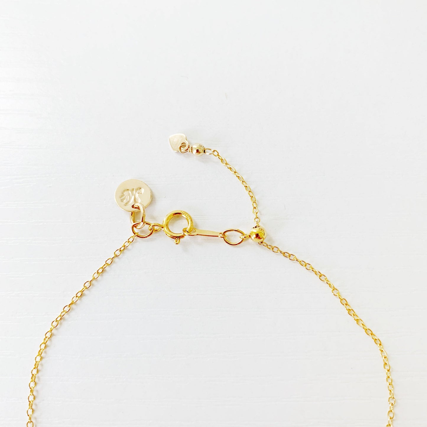 this is an image of the back of the newport pearl adjustable bracelet. it shows just the back half of the bracelet photographed on a white surface featuring the slide bead and clasp with 14k gold filled chain