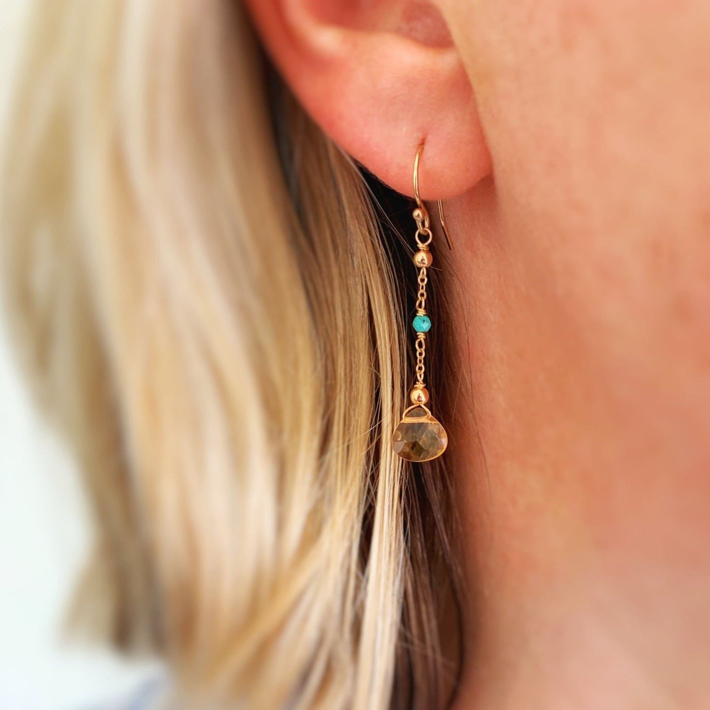 The ray of sunshine earring shown on a person's ear