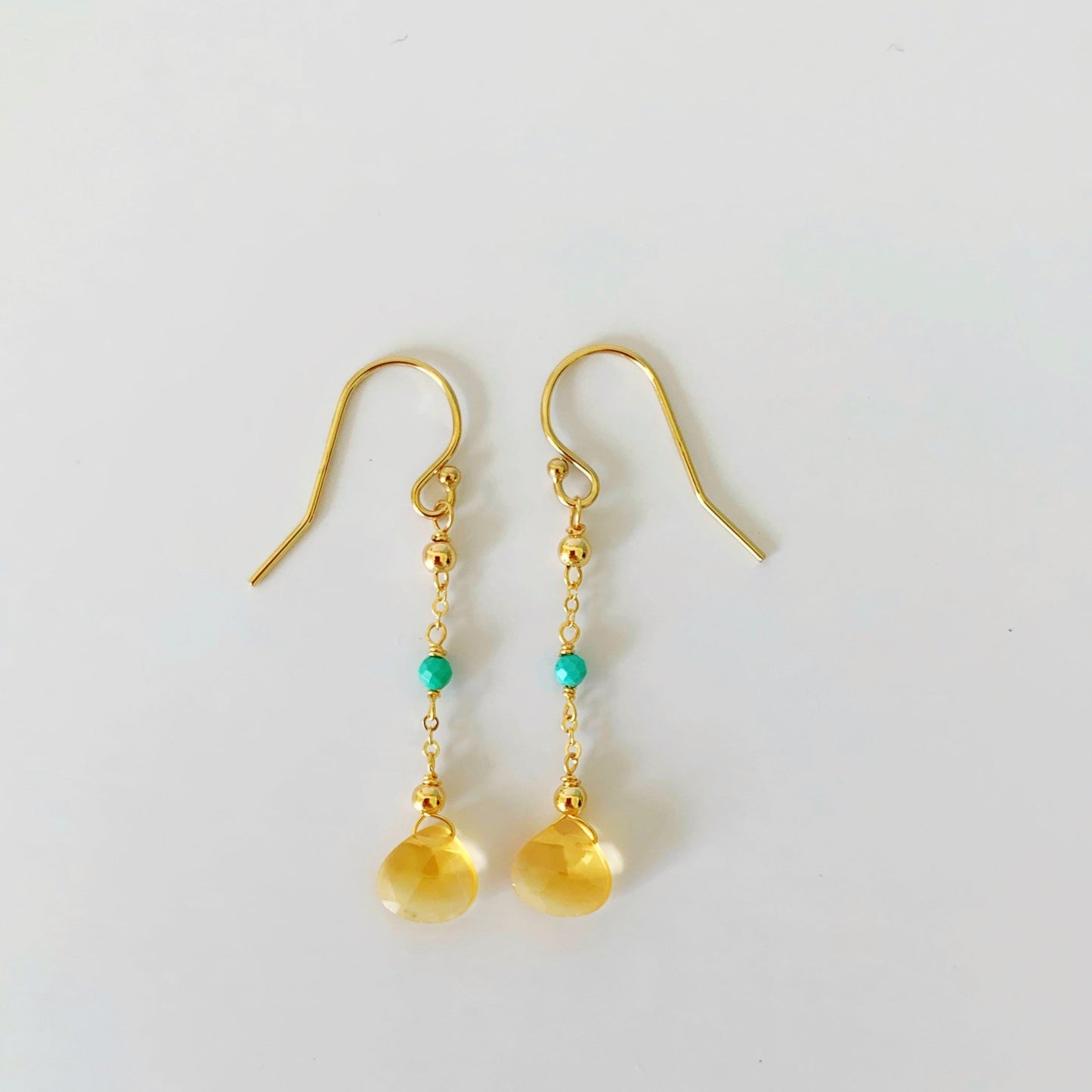 ray of sunshine earrings are designed by mermaids and madeleines they have yellow citrine drops suspended by 14k gold filled chain and findings with natural turquoise. this pair is pictured on a white background