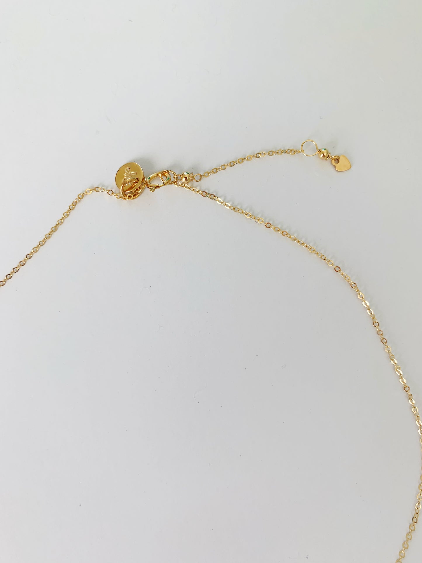 The ray of sunshine necklace has a spring ring clasp and 1" chain extender. its pictured here on a white surface