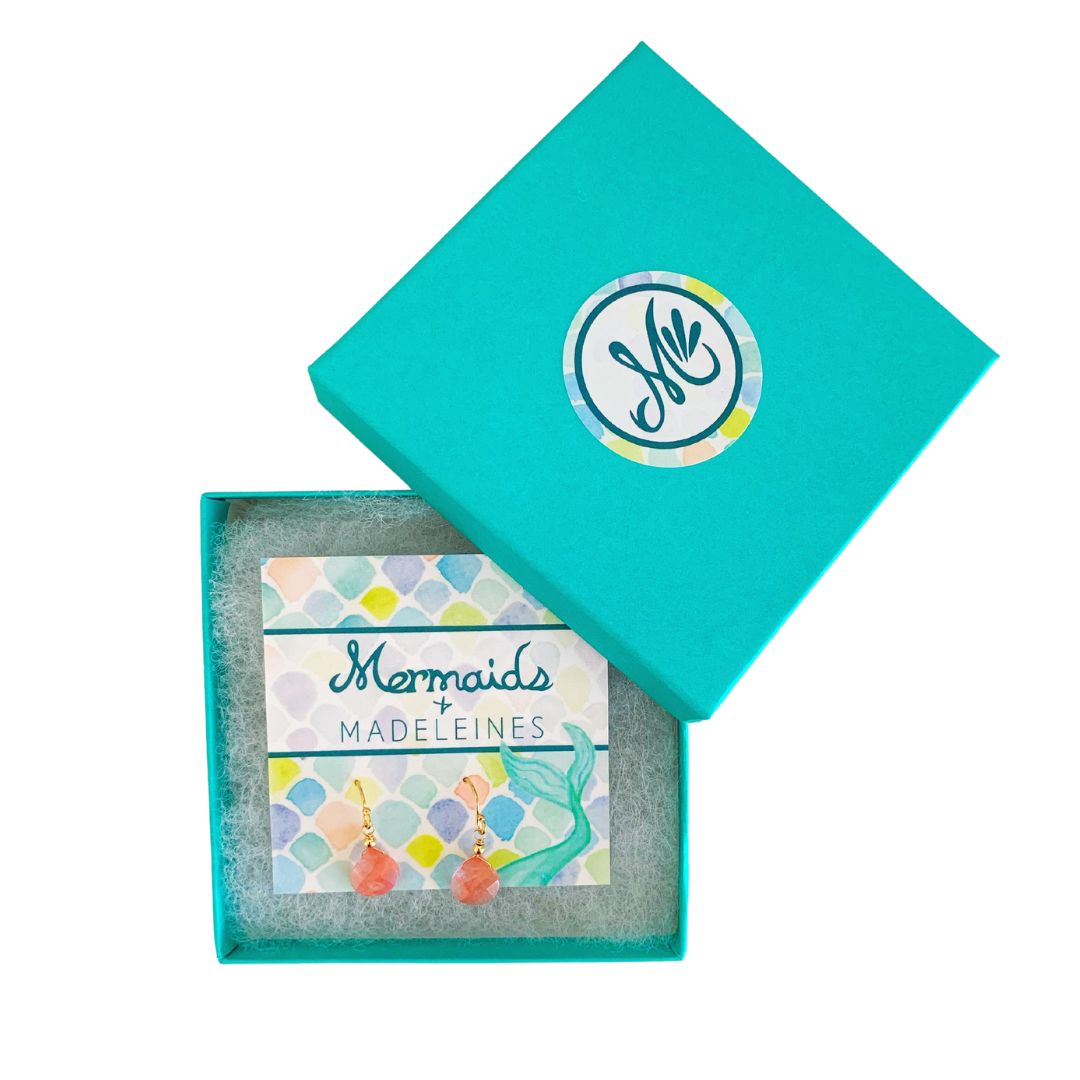 Chatham Earrings by Mermaids and Madeleines feature cherry quartz briolette drops and 14k gold filled findings. this pair is on a branded card and resting in a cotton lined teal gift box with a white background