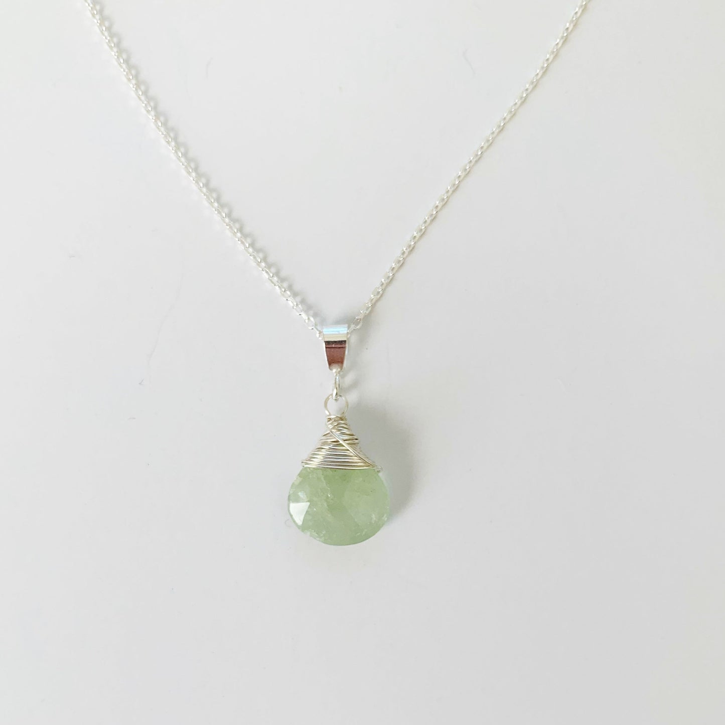 Raindrop necklace by mermaids and madeleines is a sterling silver wire wrapped pendant necklace with aquamarine. this necklace is photographed on a white surface