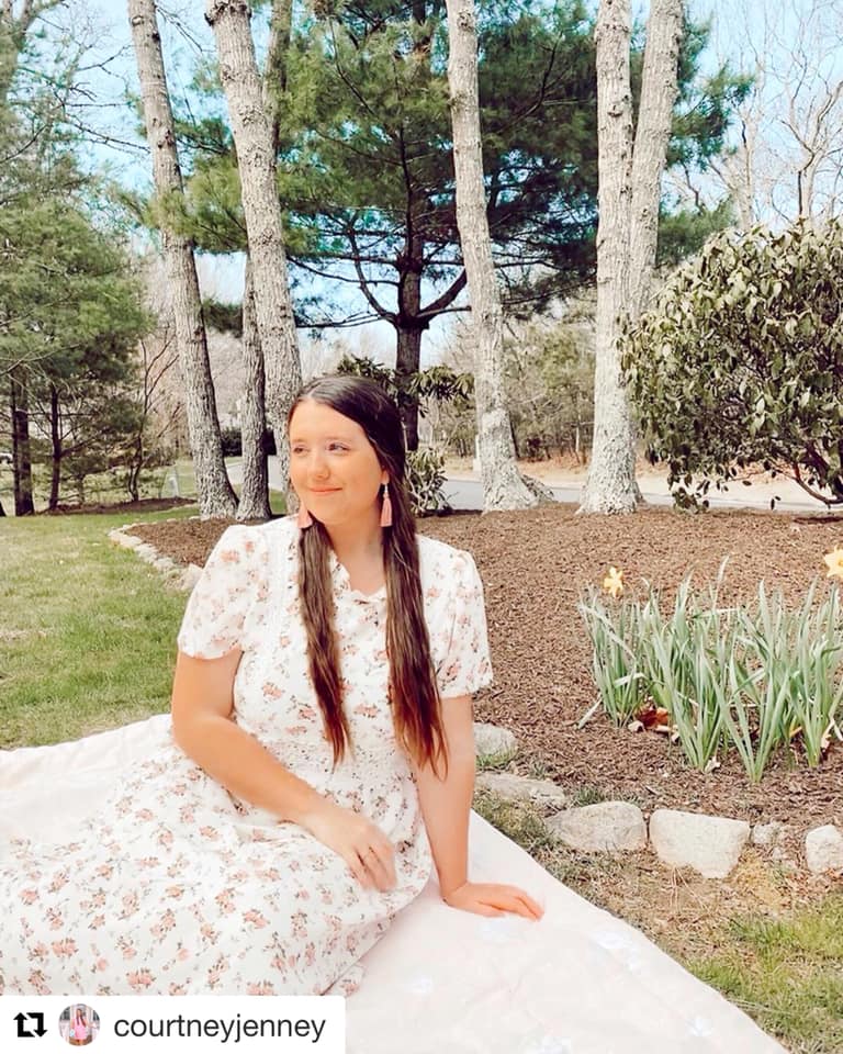 New England Influencer Courtney Jenney featured in flower dress wearing blush tassel earrings in a garden