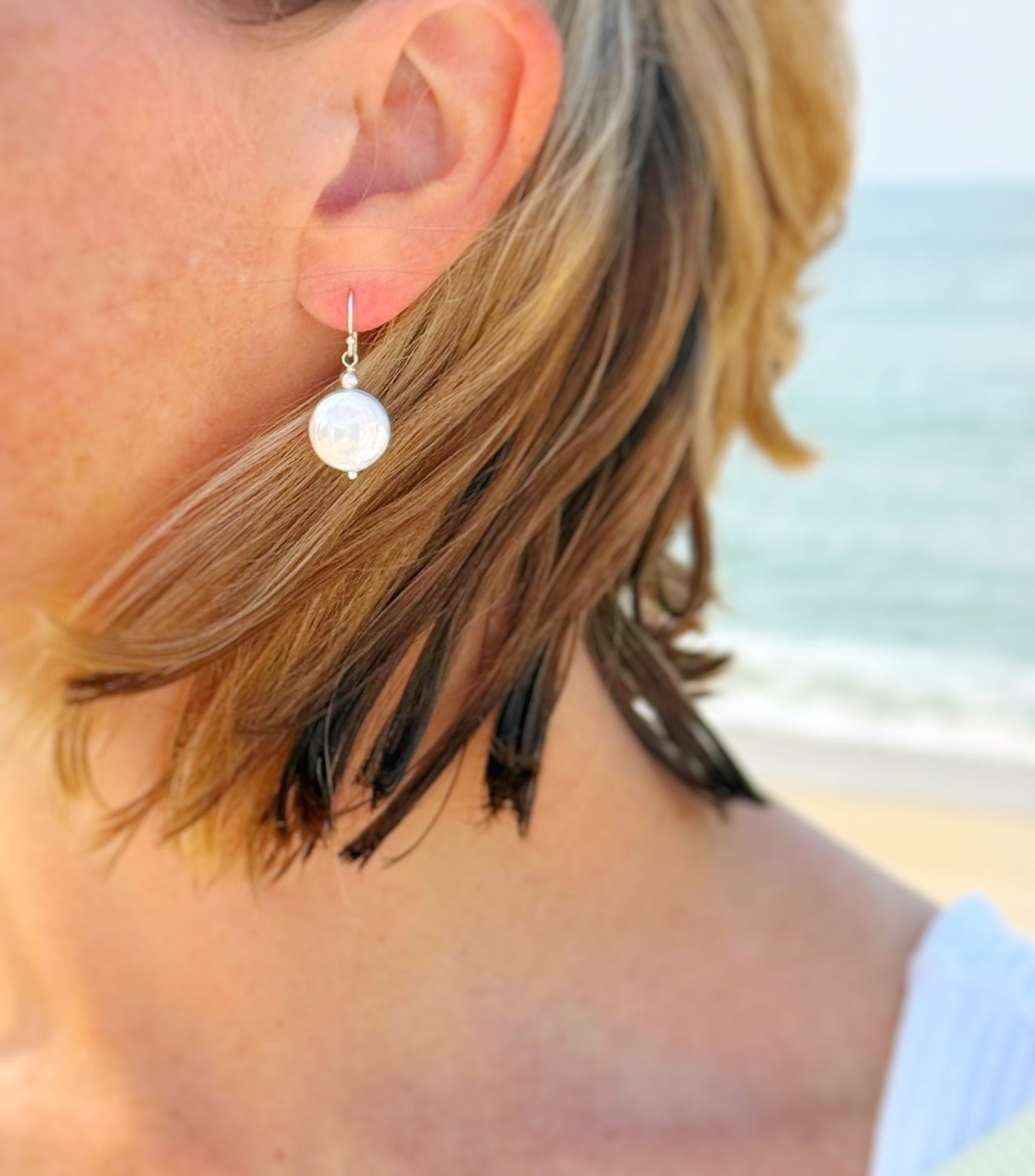 The cover photo for the View all earrings collection is the newport pearl dangle earring on a wearer