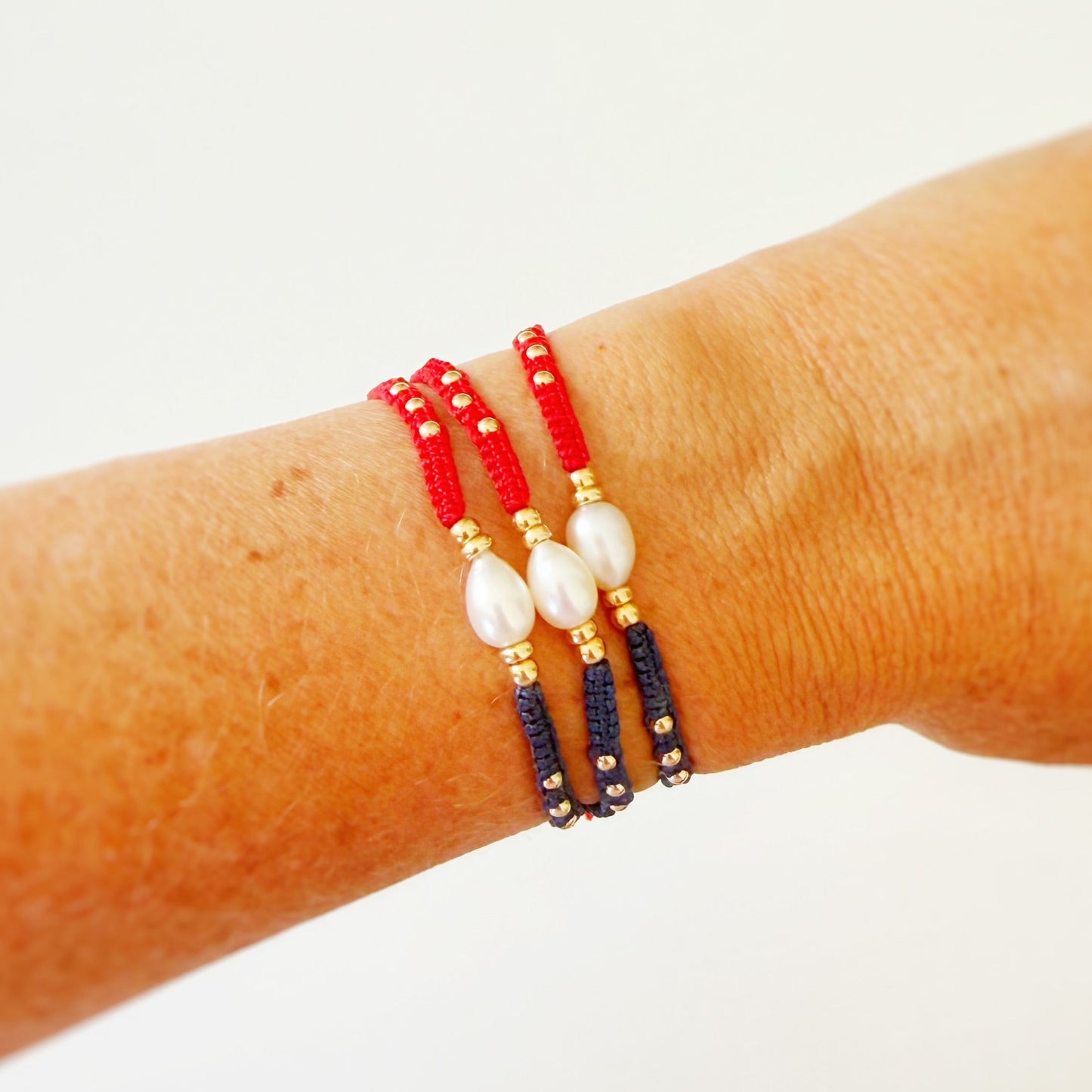 Beaded bracelet with red, gold, and black beads on a wrist against a white background