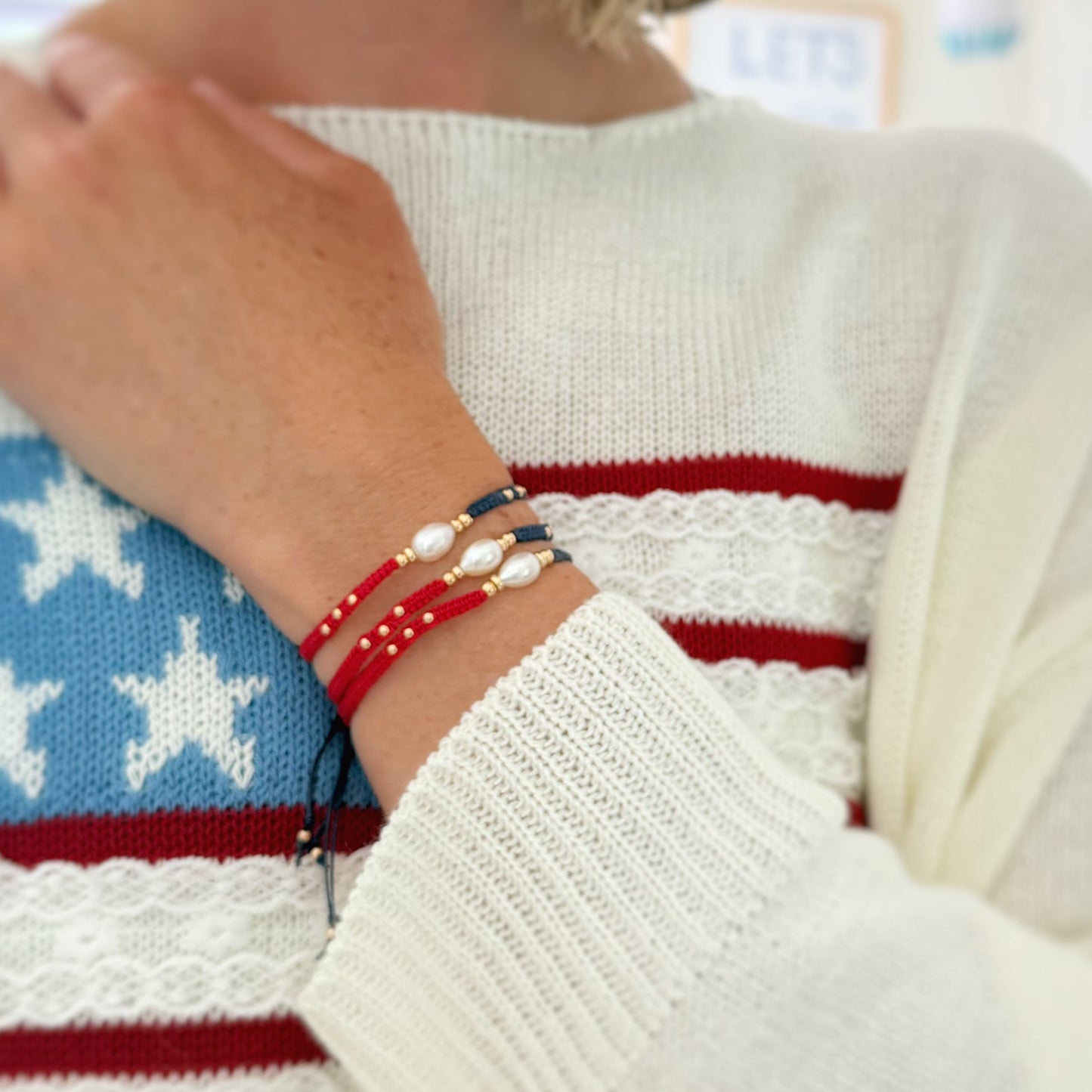 Close-up of a person wearing multiple bracelets on a sweater with star and stripe pattern