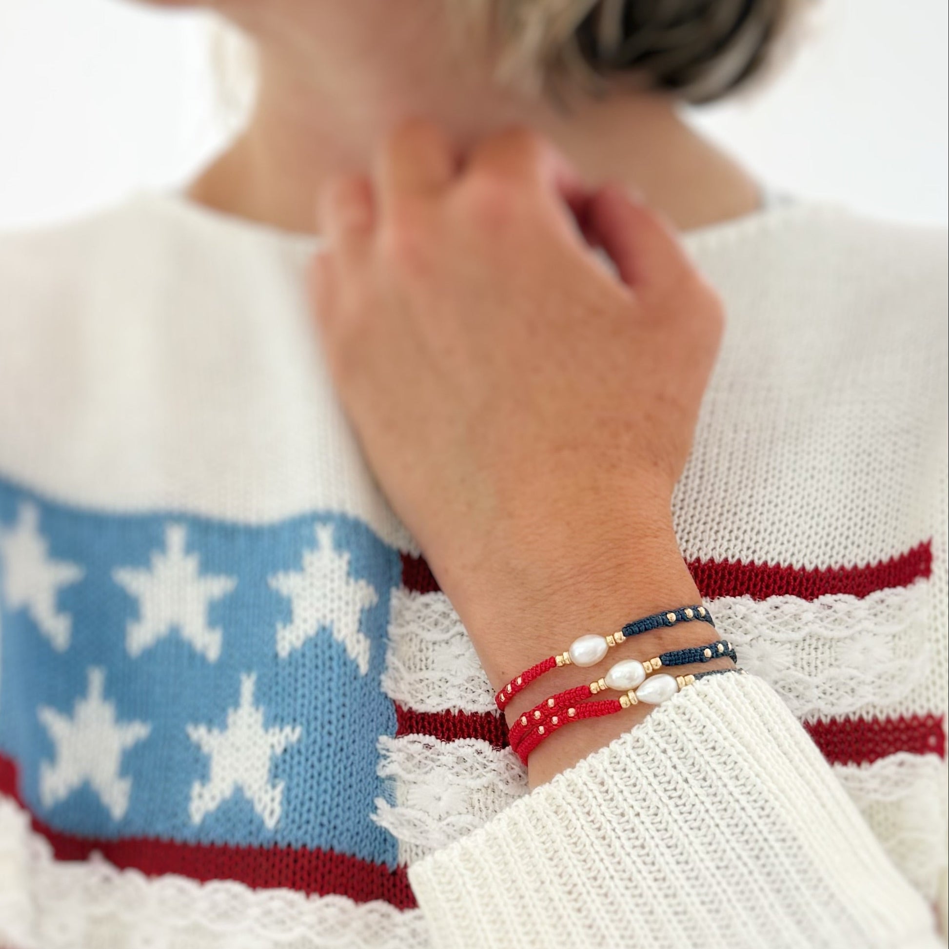 Person wearing a sweater with American flag design and colorful bracelets.