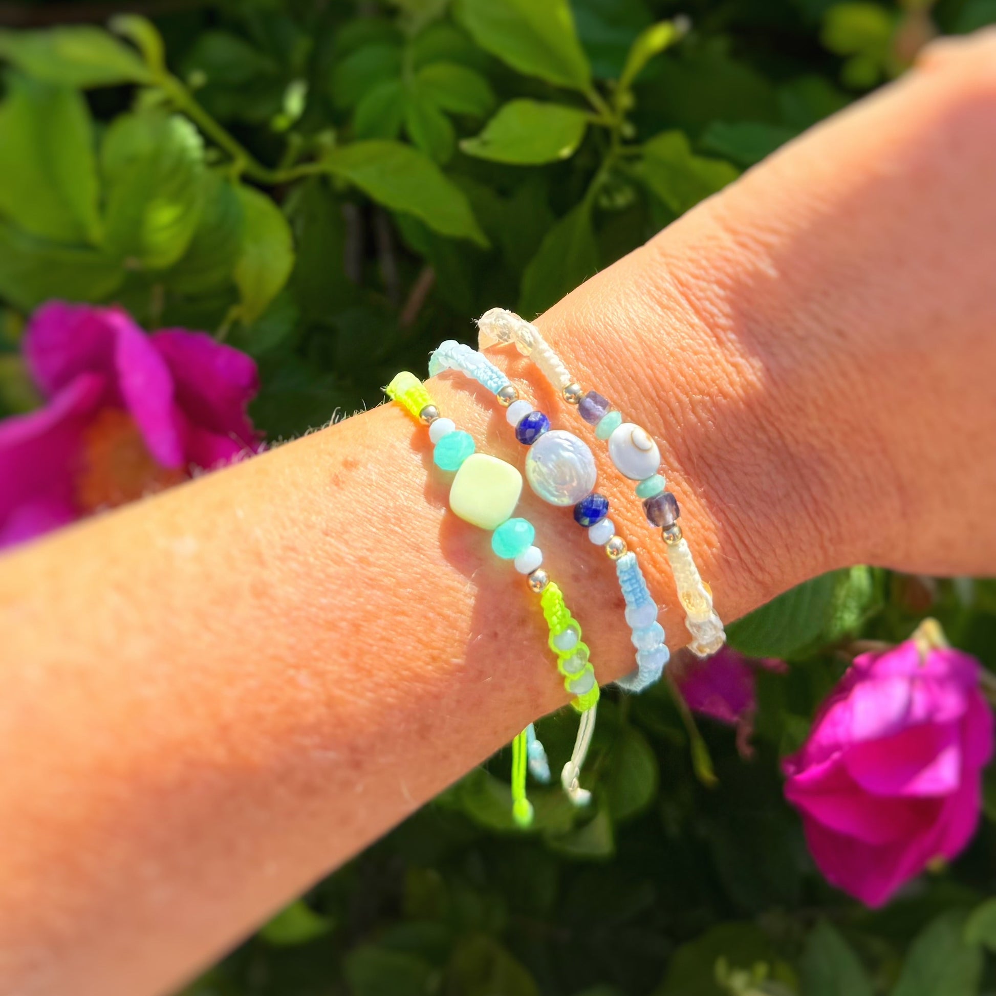 Close-up of a wrist wearing multiple woven bracelets beads with a blurred natural background