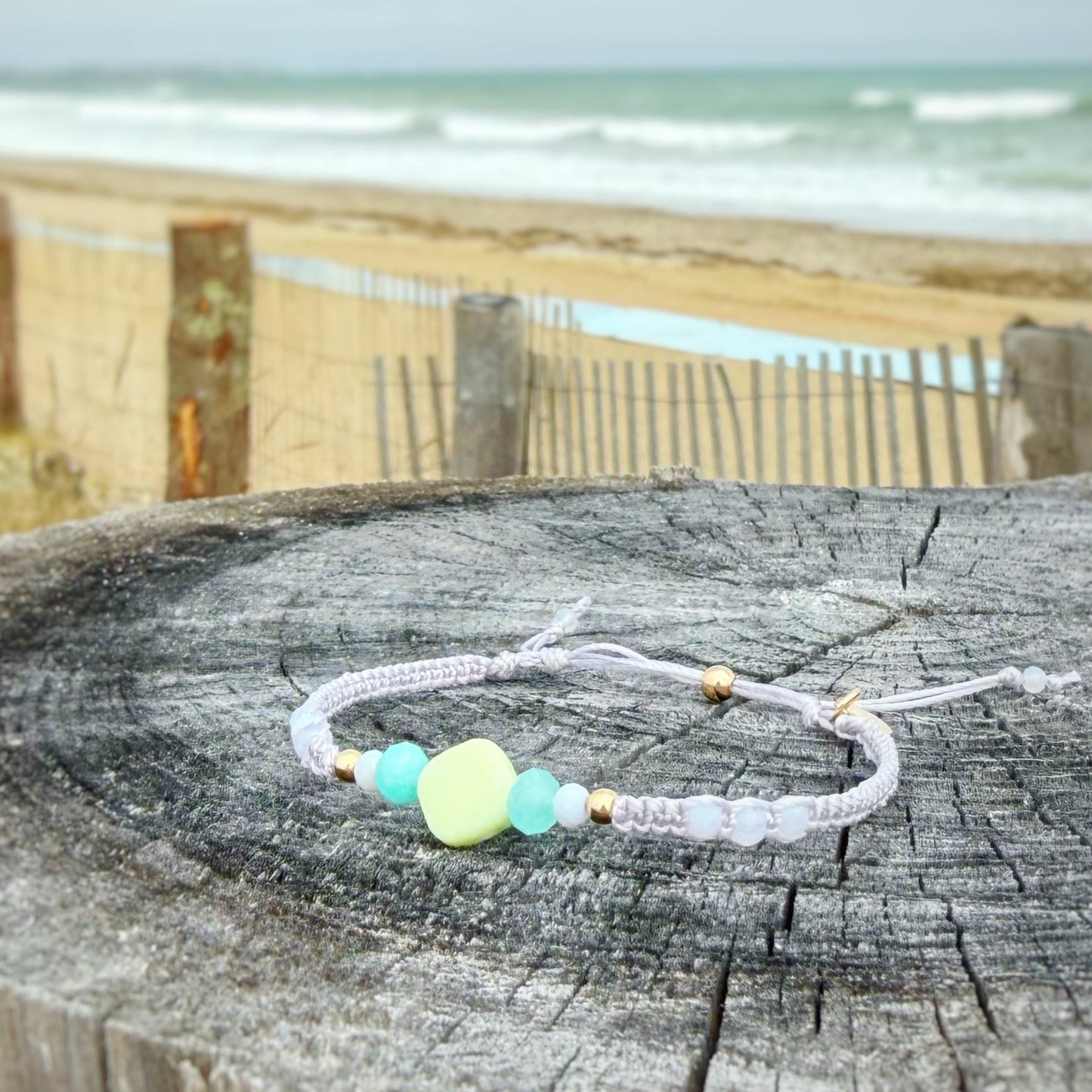 Light purple macrame Bracelet with a lime green bead at the center on a wooden post by the beach