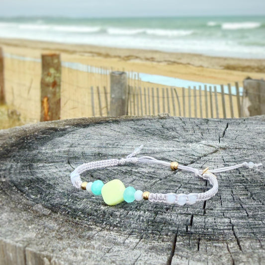Light purple macrame Bracelet with a lime green bead at the center on a wooden post by the beach
