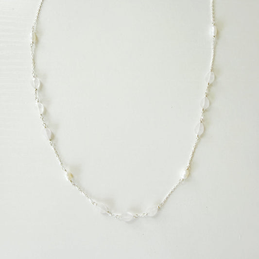 A delicate silver-toned chain necklace featuring small, irregular white pears and light pink kunzite beads spaced along the chain, displayed against a plain white background.