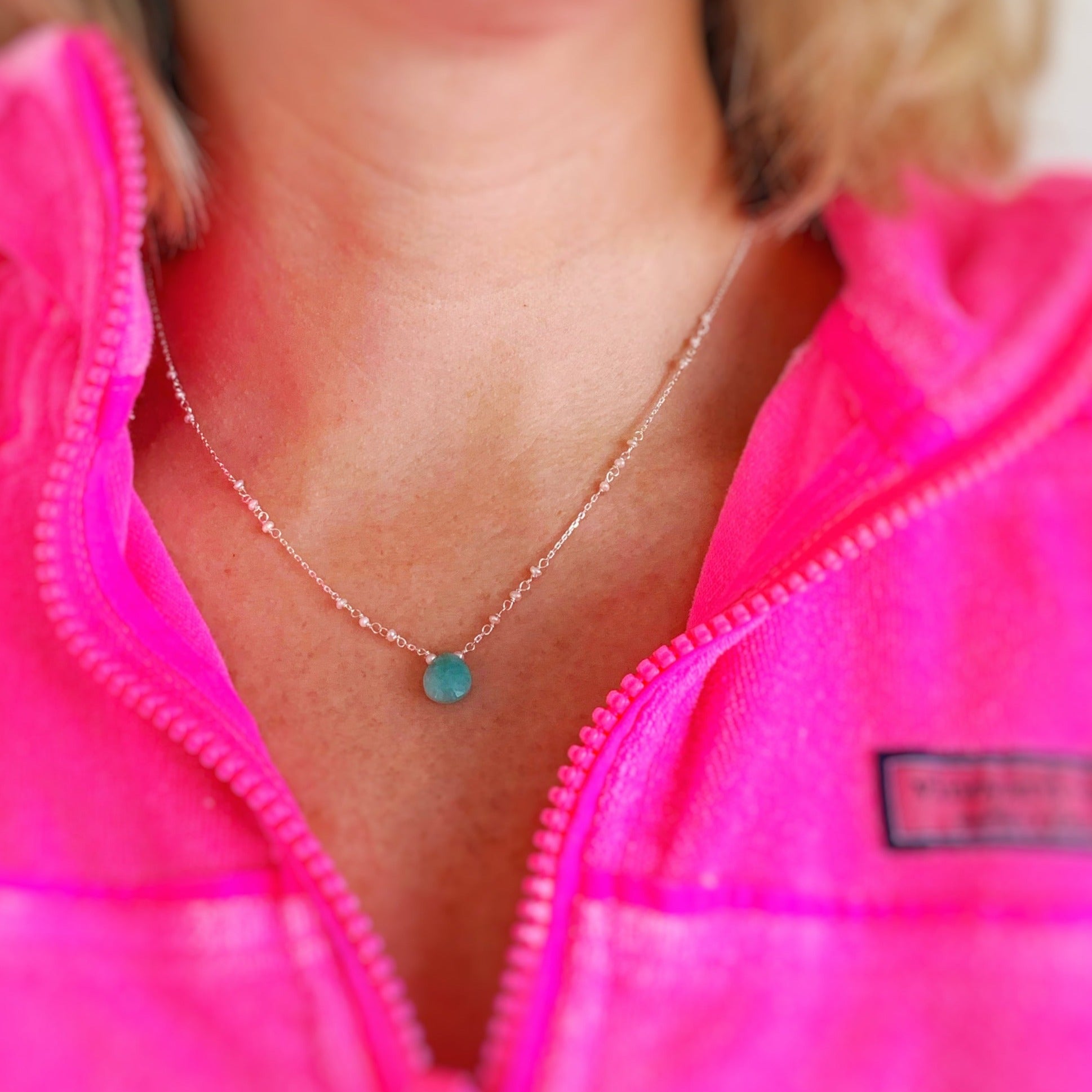 Mermaids and madeleines island air necklace in sterling silver is a necklace with an amazonite drop at the center and sterling chain with freshwater pearls. This is a photograph of a person wearing the necklace for a better idea of size