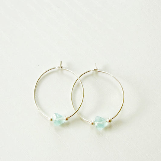 sterling silver hoop earrings with light blue gemstones on a white background