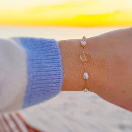 Close-up of a wrist wearing a pearl bracelet with a blurred background