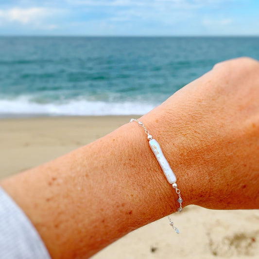 Image of the Truro bracelet in sterling silver photographed close up on a wrist with a soft blurry beach background