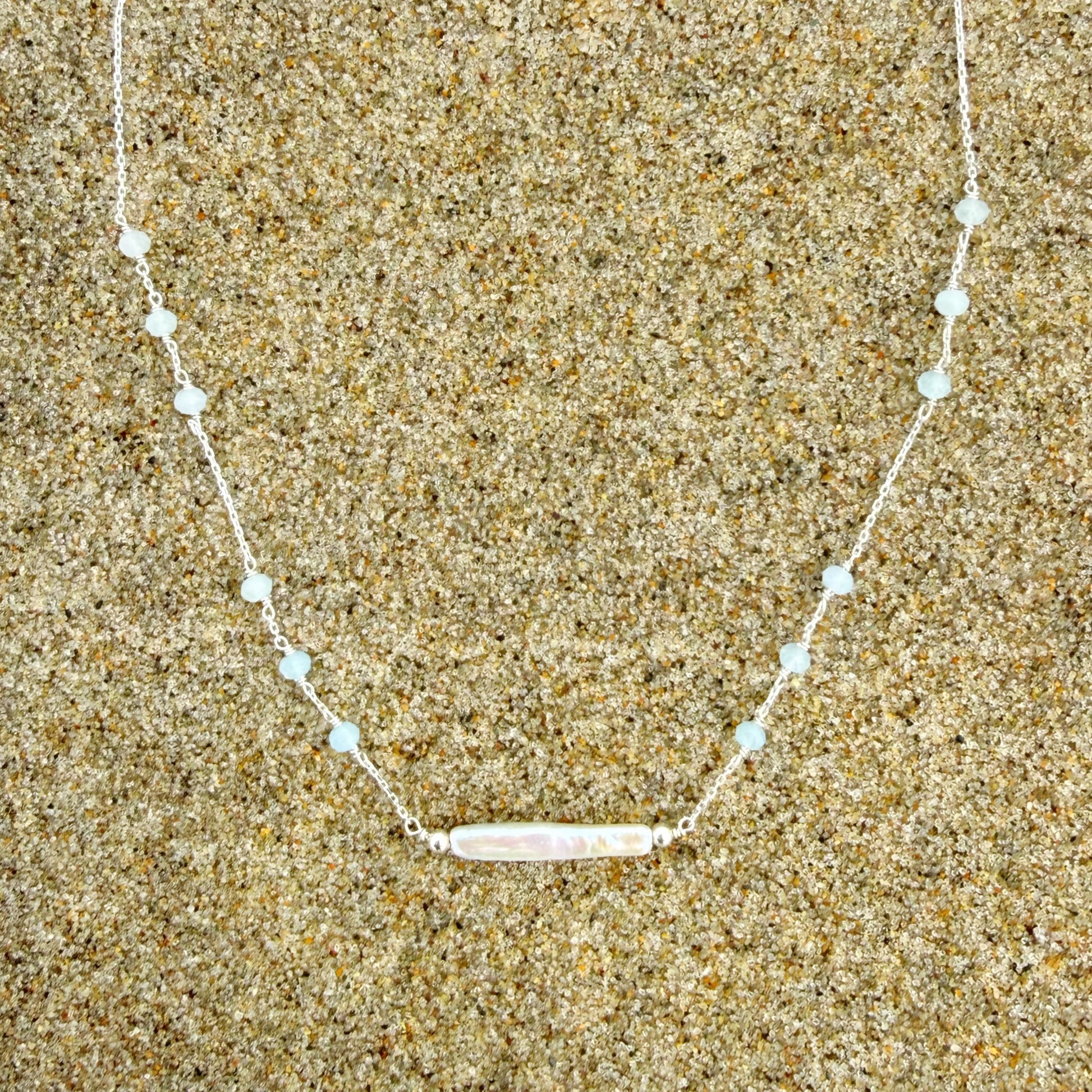 Necklace with a bar pendant on a sandy background