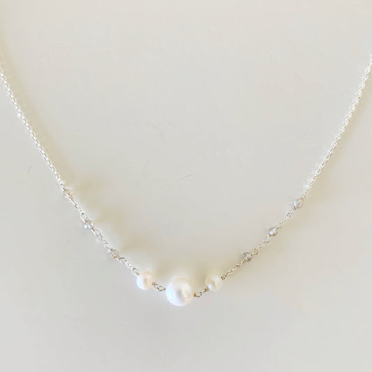 the westport necklace by mermaids and madeleines is created with sterling silver chain with hand wrapped freshwater pearls at the center and labradorite gems on the chain. this necklace is photographed closer up on a white surface