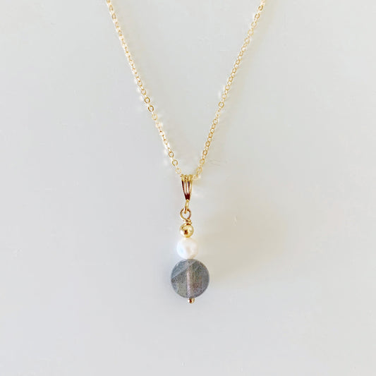 The Arctic pendant by mermaids and madeleines is created with a small freshwater pearl and a faceted labradorite coin with 14k gold filled chain and findings. this pendant necklace is photographed on a white background