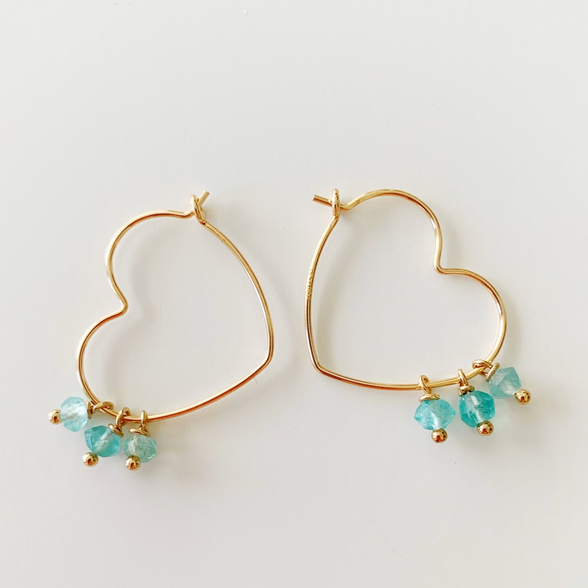 beach lover hoops by mermaids and madeleine are created with 14k gold filled wire and apatie beads. this pair is heart shaped and photographed on a white surface