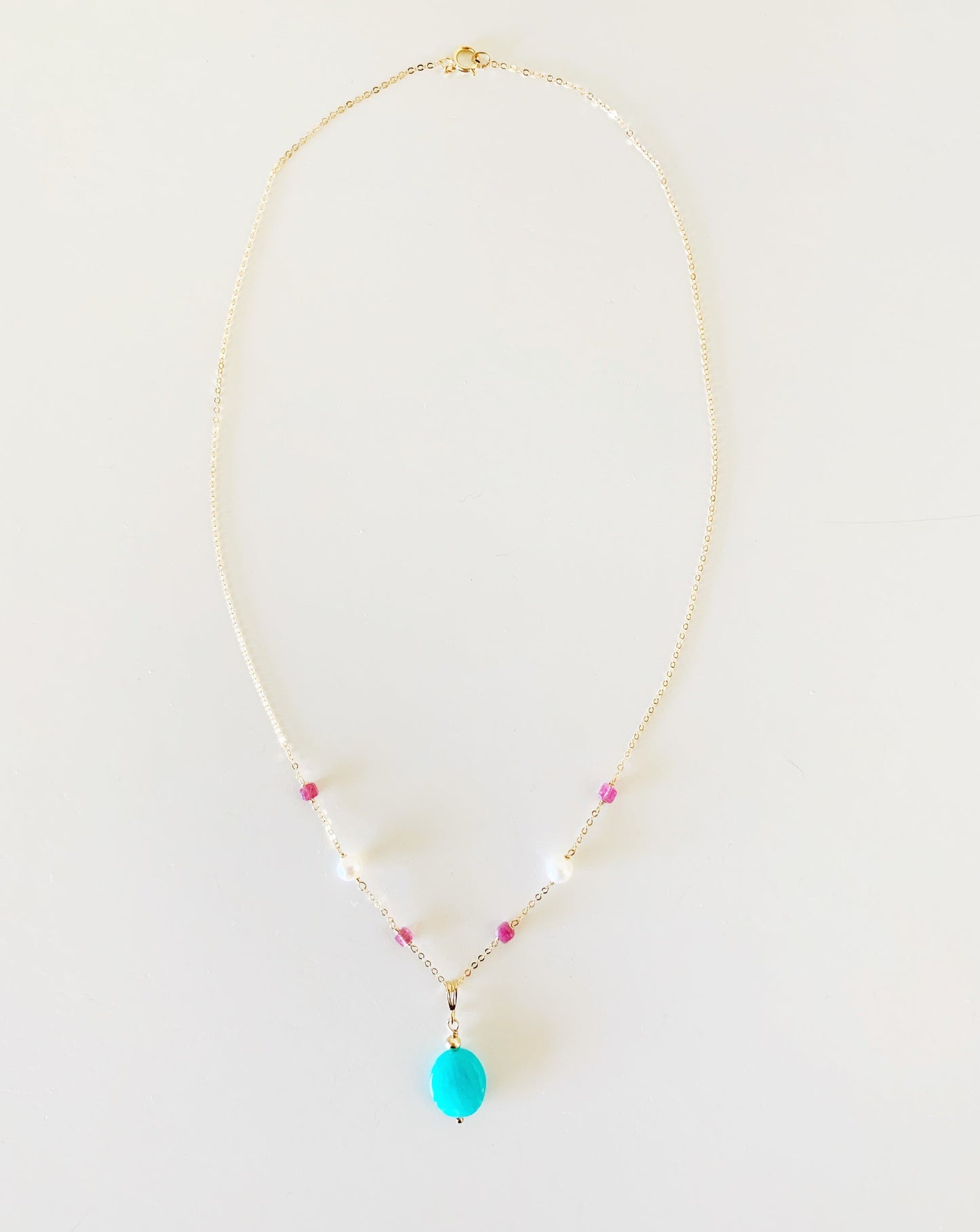 the harwich port necklace by mermaids and madeleines is a pendant style necklace with a bright amazonite stone suspended from 14k gold filled chain with tourmaline and freshwater pearl on the chain. this necklace is in full view and photogrpahed on a white surface
