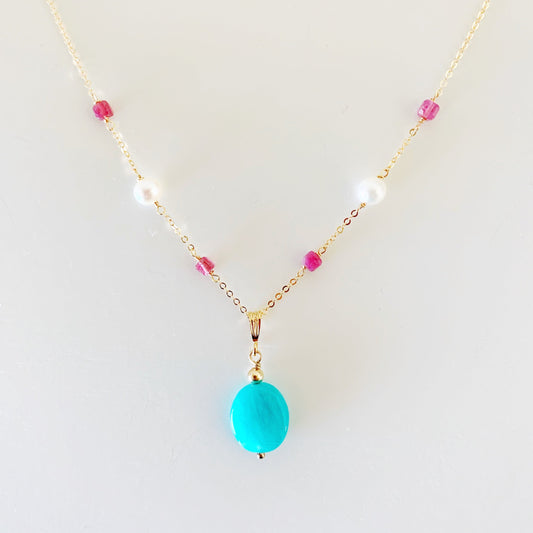 the harwich port necklace by mermaids and madeleines is a necklace a pendant style featuring a bright amazonite stone suspended from 14k gold filled chain with pink tourmaline and glowing freshewater pearls. this necklace is viewed closer up and photographed on a white surface