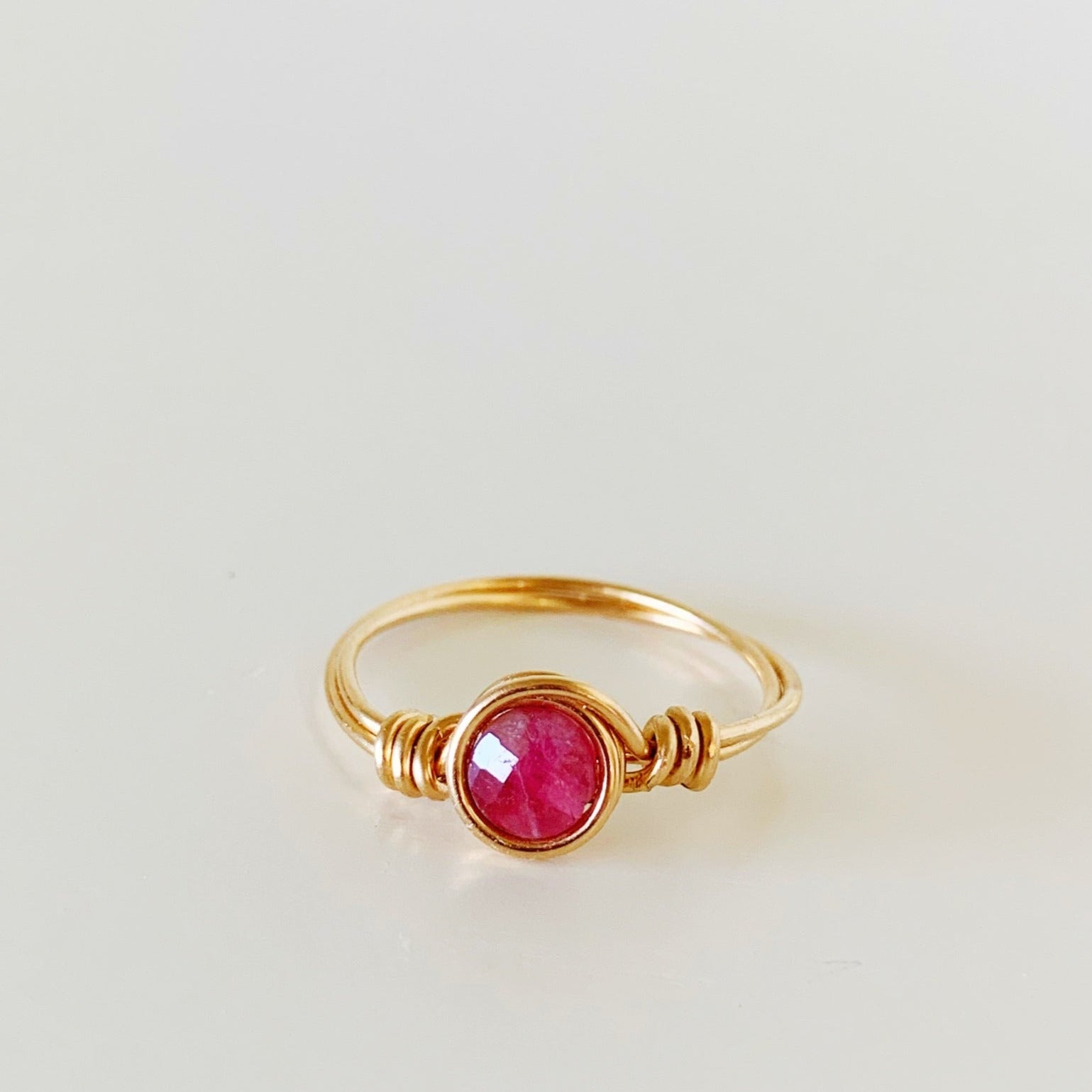 the harwich port ring by mermaids and madeleines is a wire-wrapped ring with 14k gold filled wire and a pink tourmaline faceted coin bead. this ring is photographed facing forward on a white surface