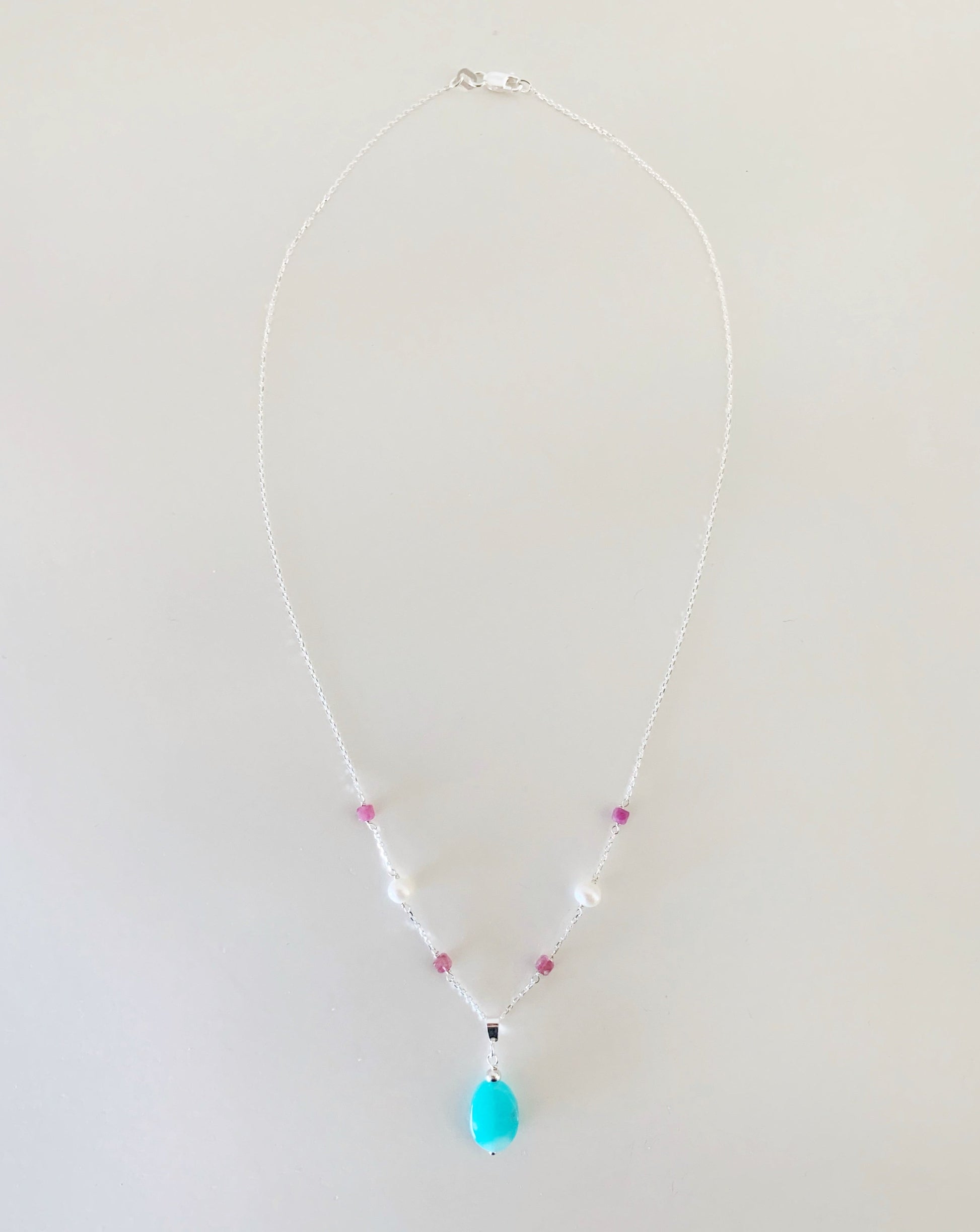 the harwich port necklace by mermaids and madeleiens is a pendant style necklace with amazonite suspended from sterling silver with pink tourmaline and freshwater pearls this necklace is full length view and photographed on a white surface