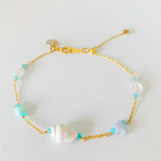 the island hopper adjustable bracelet is on 14k gold filled chain with a slide clasp and stations of shell and semiprecious beads. this bracelet is photographed on a white surface