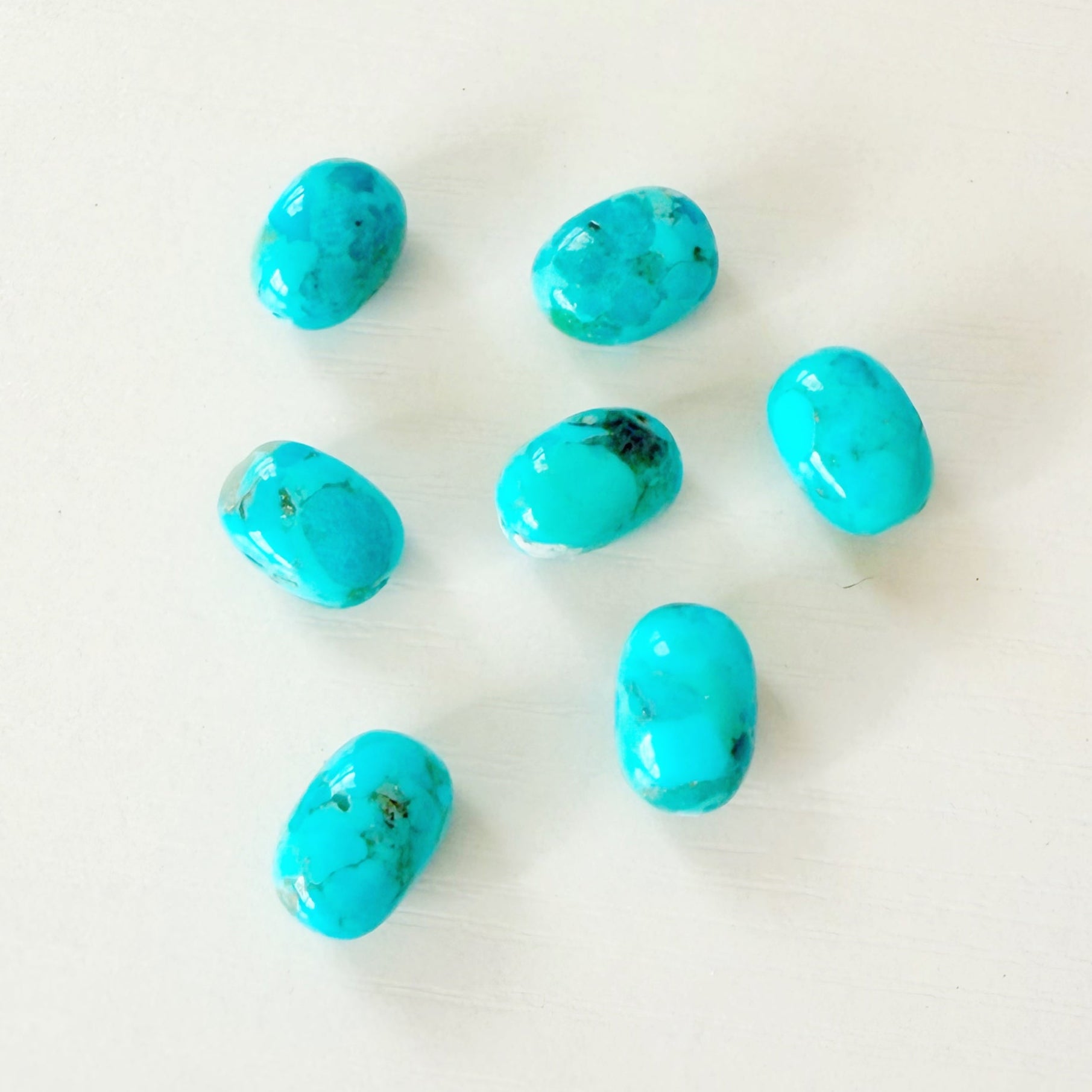 Turquoise beads scattered on a white background