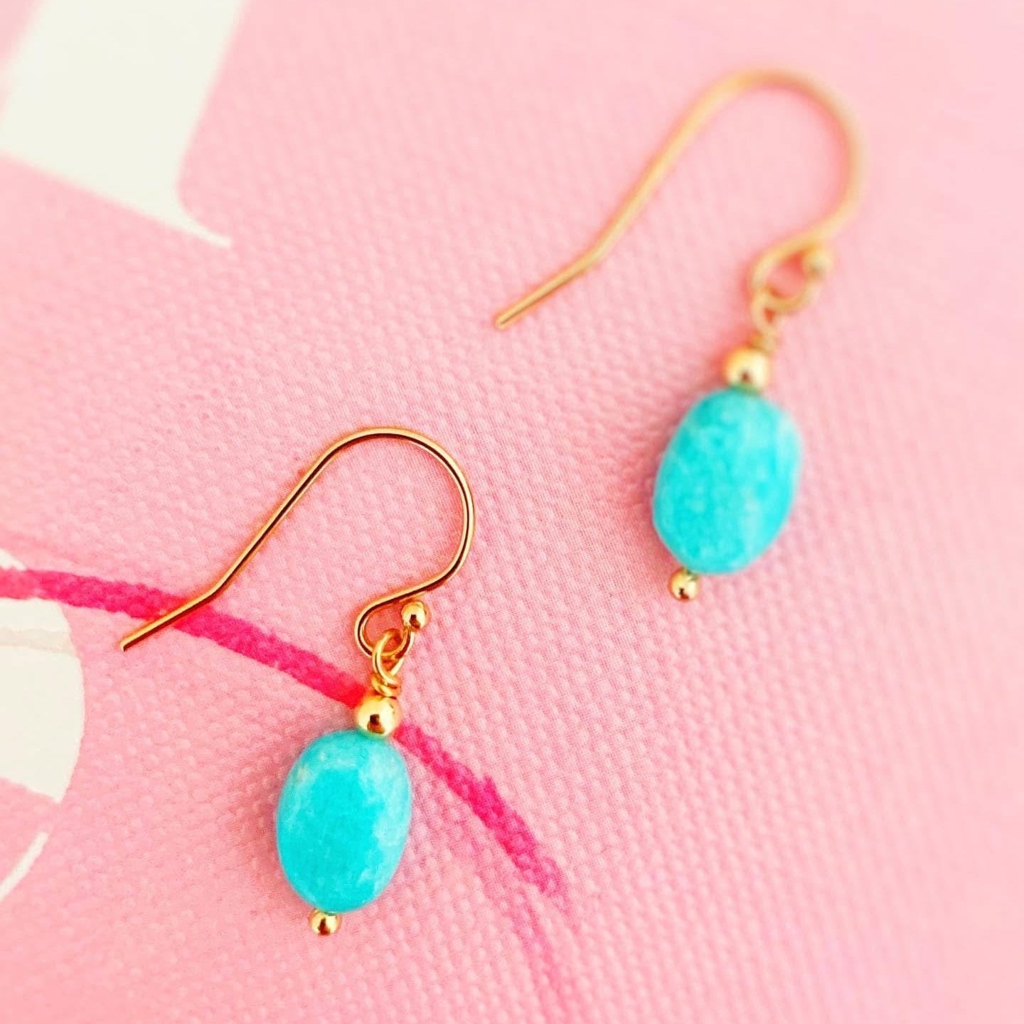 Turquoise amazonite earrings with gold hooks on a pink background