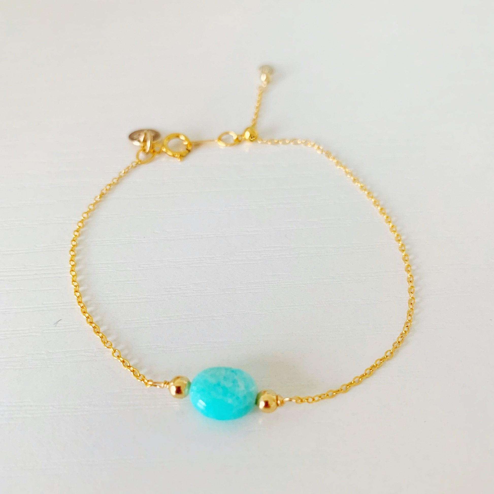 laguna adjustable bracelet is created on a thin 14k gold filled chain with an oval amazonite bead at the center. this bracelet is photographed on a white surface