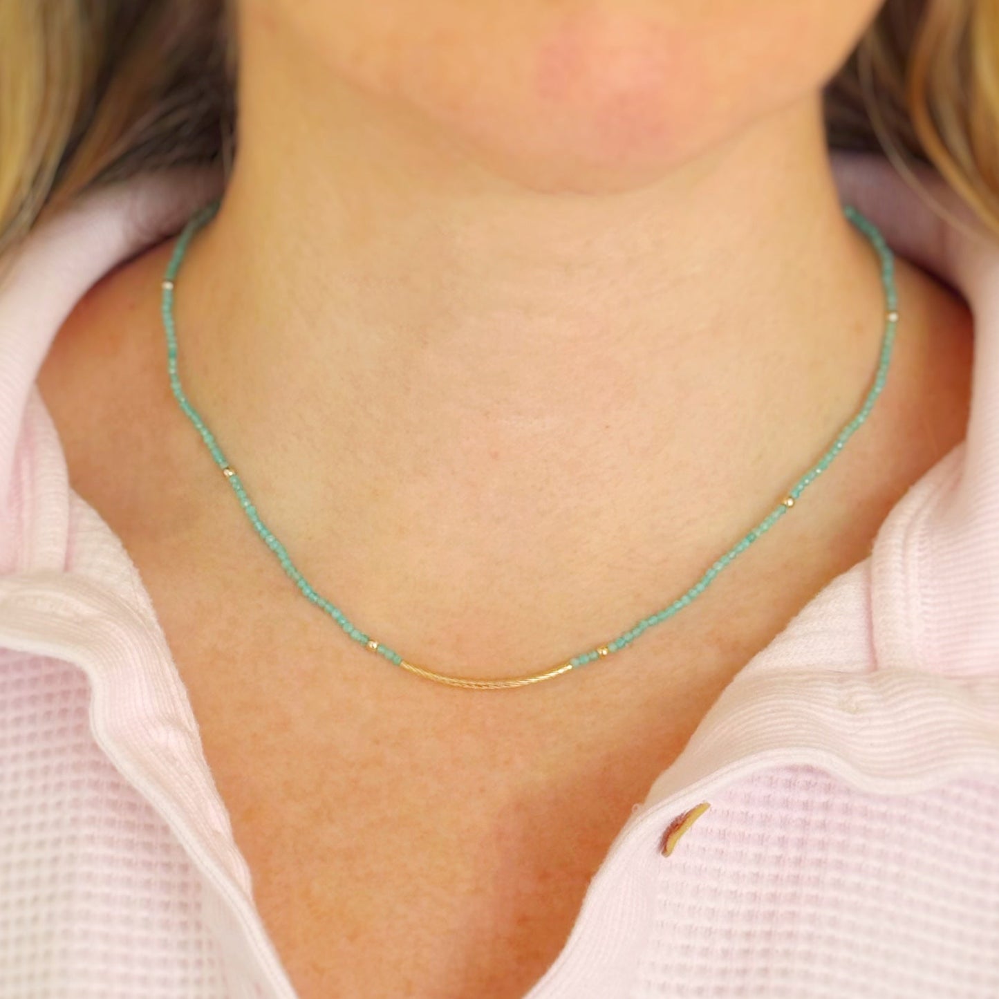Close-up of a amazonite beaded necklace on a person wearing a light pink top.