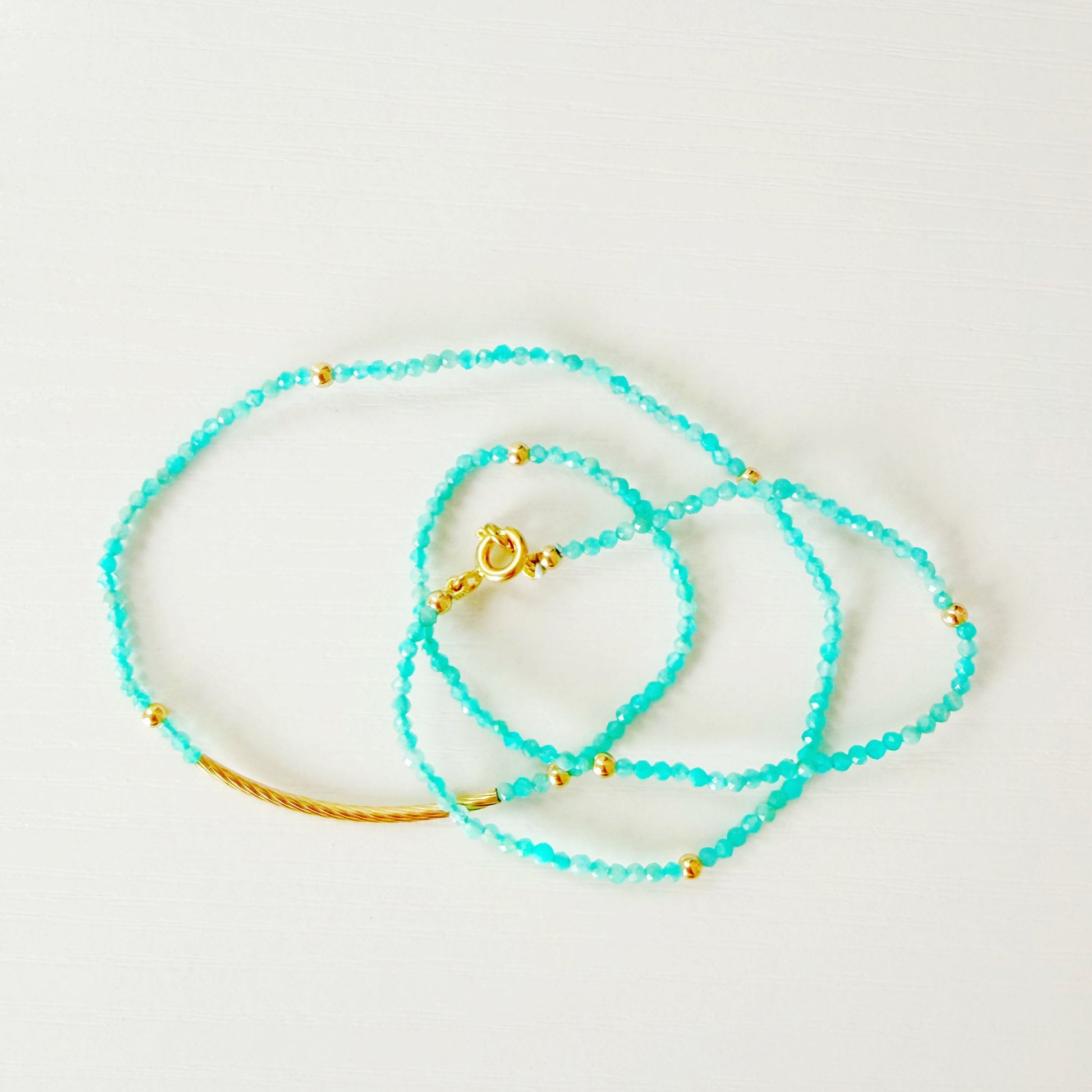 amazonite and gold beaded necklaces on a white background