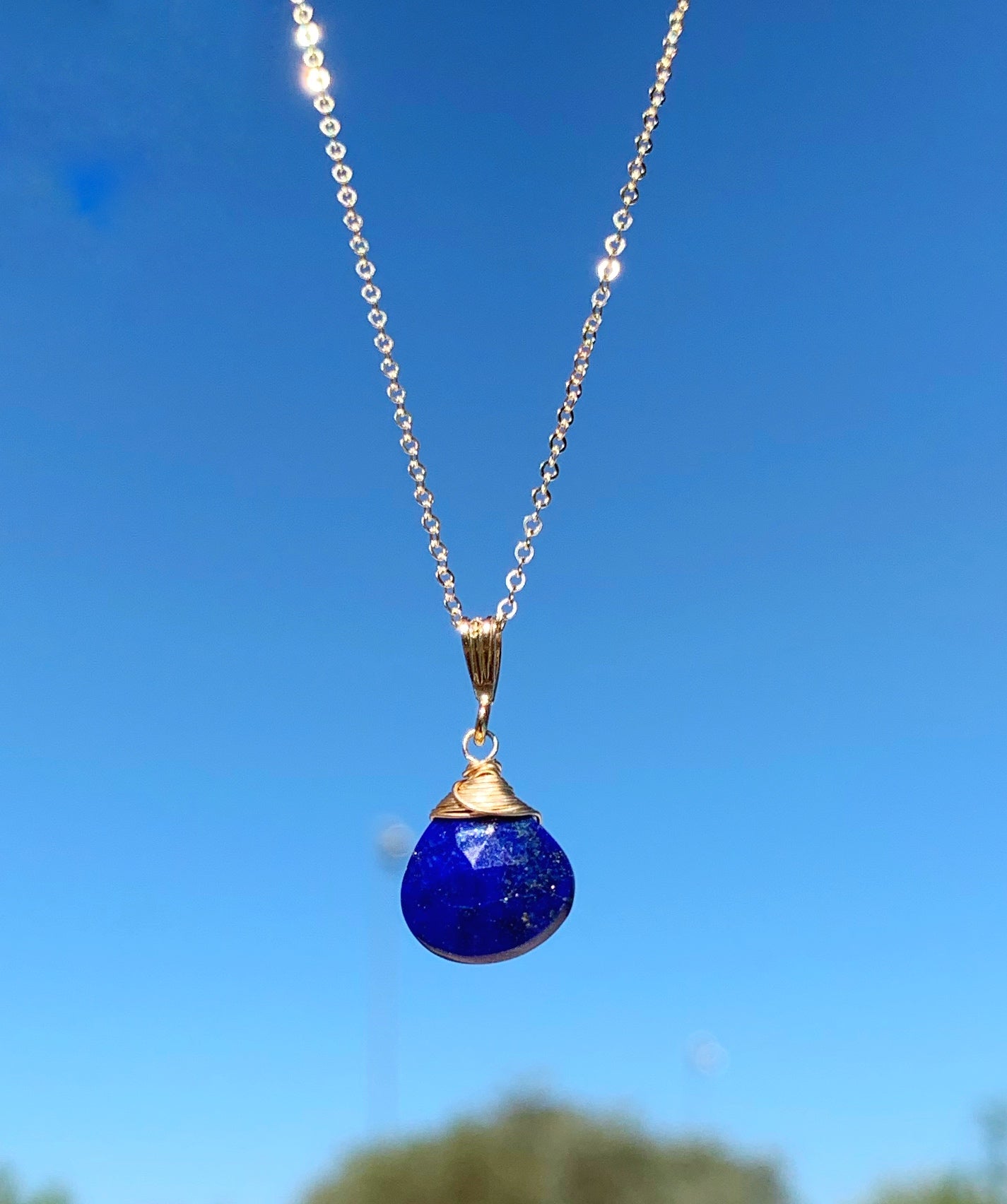 the mermaids and madeleines neptune necklace is created with blue lapis and 14k gold filled findings and chain. this one is suspended with blue sky in the background!