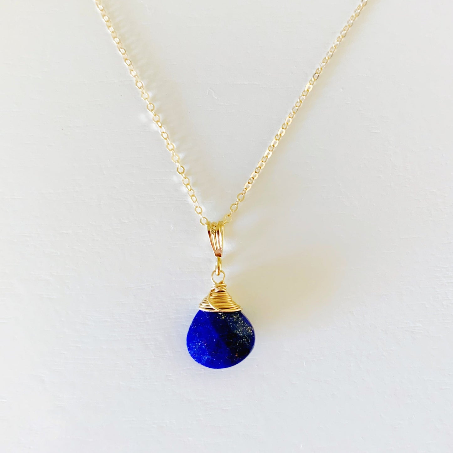The Neptune pendant necklace by mermaids and madeleines is designed with lapis and 14k gold filled findings and chain. This necklace is photographed on a white surface