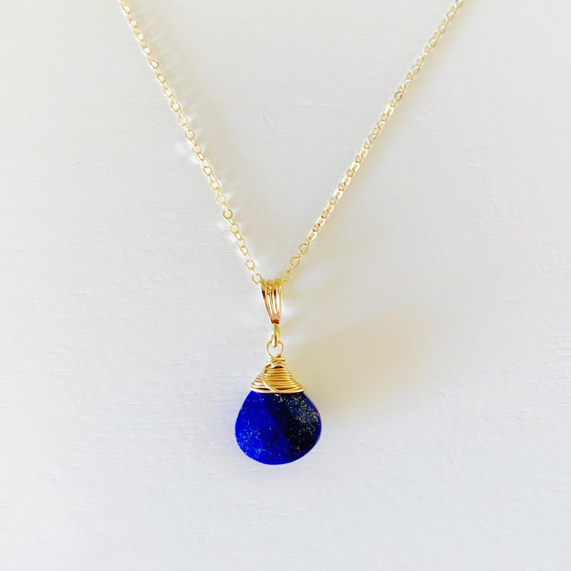 The Neptune pendant necklace by mermaids and madeleines is designed with lapis and 14k gold filled findings and chain. This necklace is photographed on a white surface
