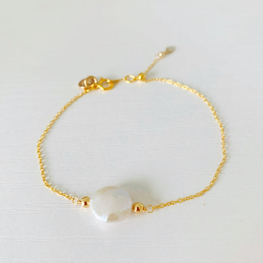 newport adjustable bracelet is a dainty style bracelet with a slide clasp, 14k gold filled chain and a freshwater coin pearl at the center. the bracelet is photographed on a white surface