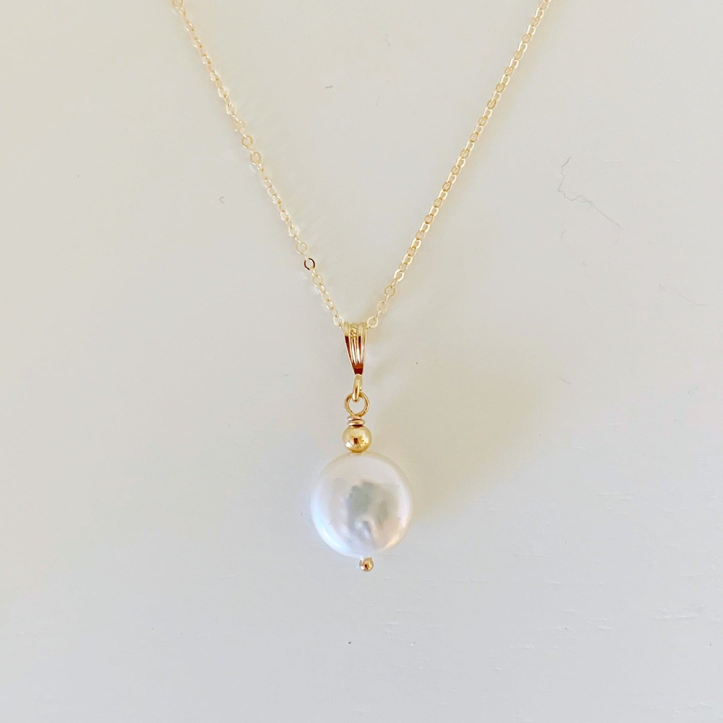 the newport necklace by mermaids and madeleines is a simple pendant style designed with a white freshwater coin pearl and 14k gold filled chain and findings