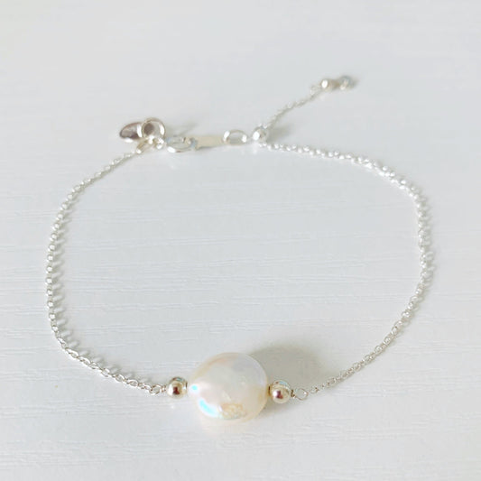 the newport adjustable bracelet is created on stelring silver cable chain with an adjustable slide clasp and a freshwater coin pearl at the center. the bracelet is photographed on the white surface