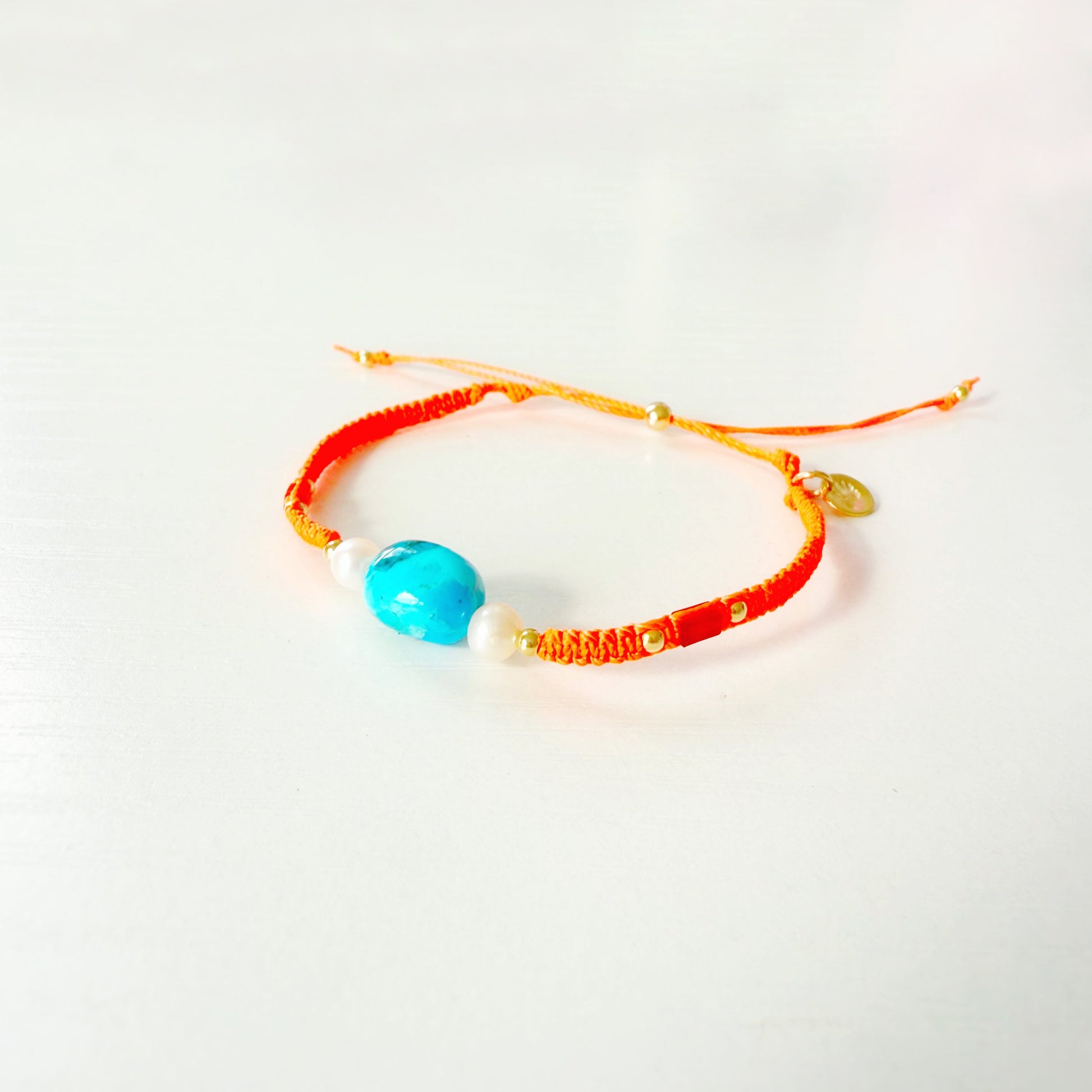 Bracelet with a blue bead and orange cord on a white background