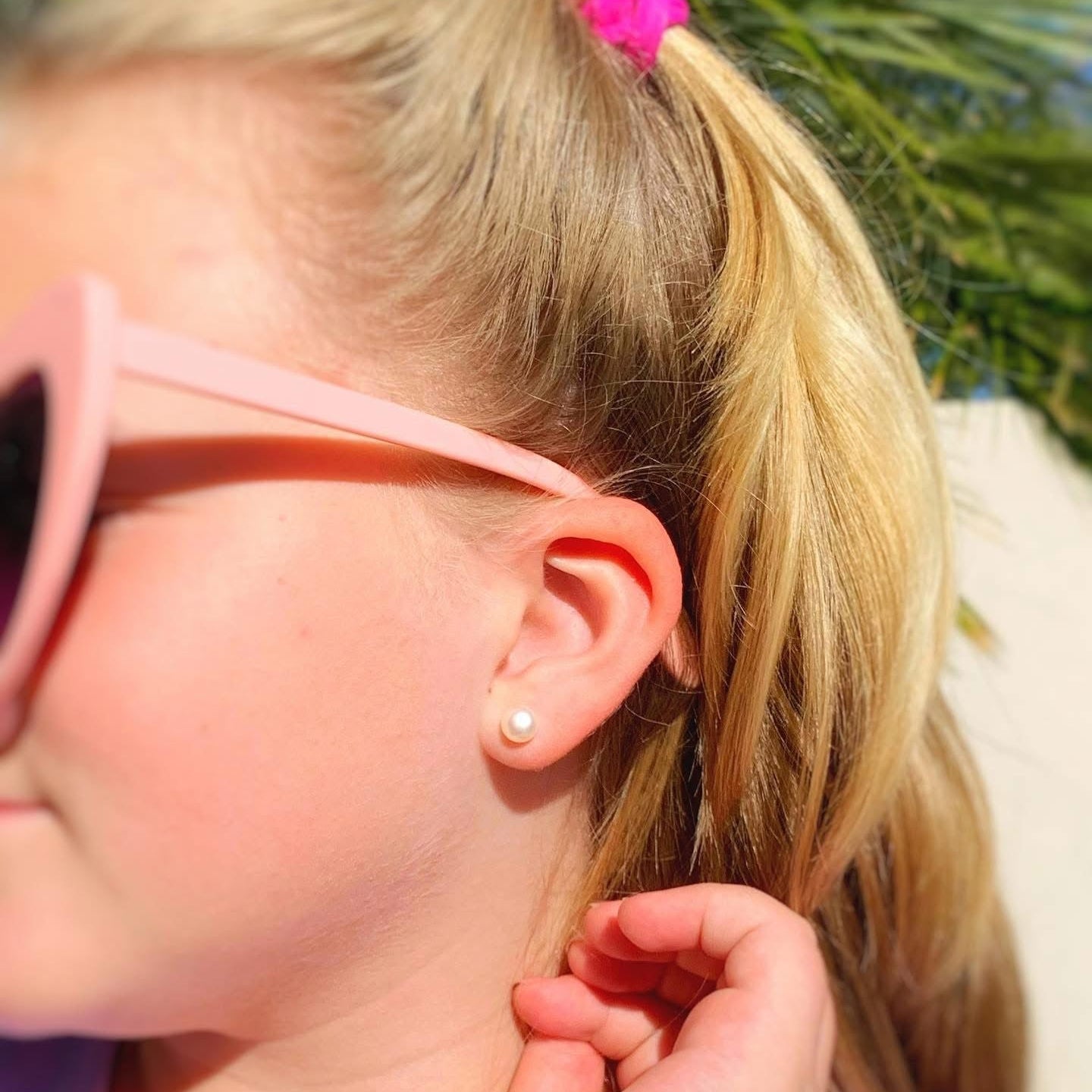 Close-up of a child wearing pink sunglasses with a blurred background