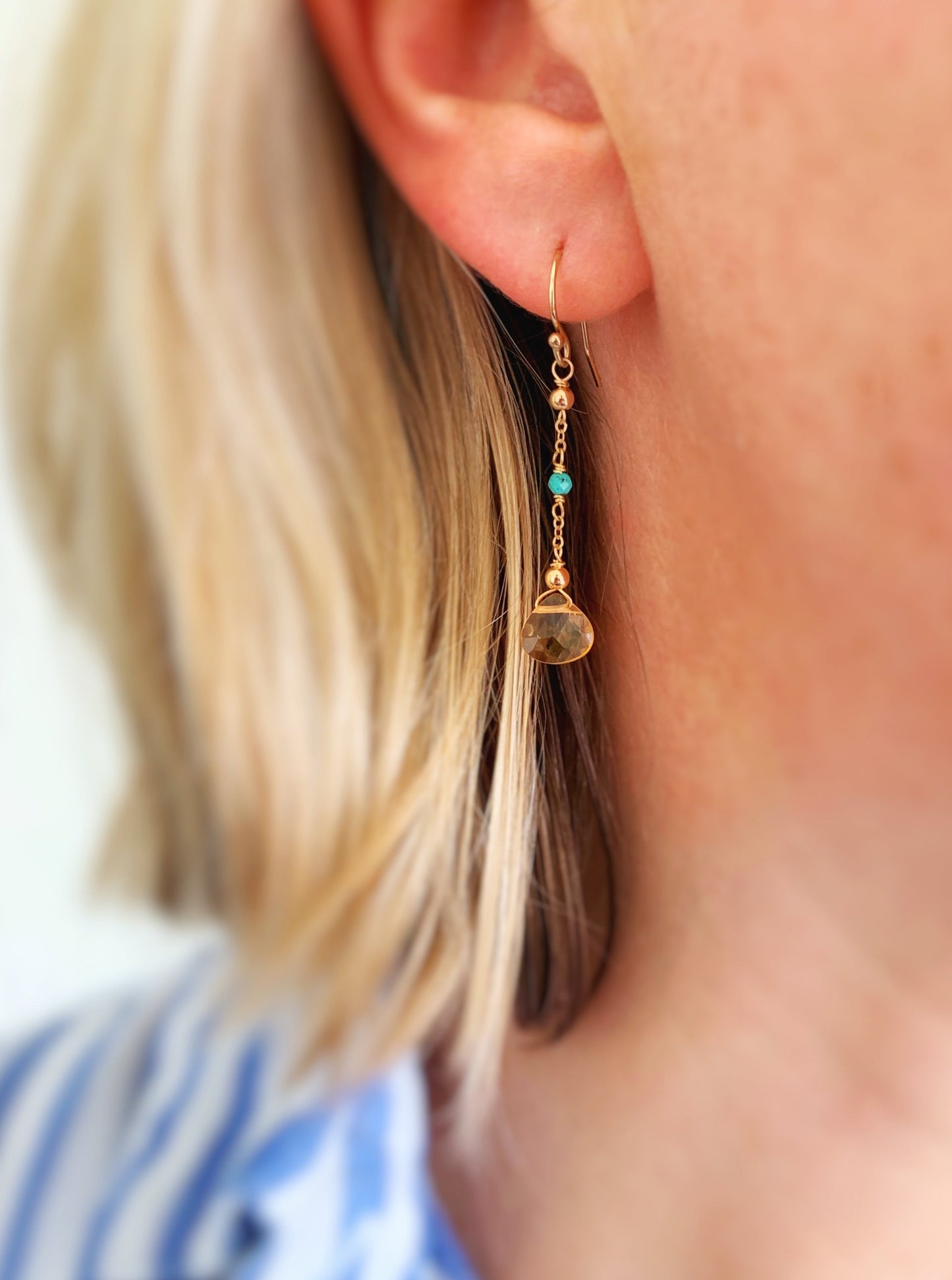 The ray of sunshine earring shown on a person's ear 