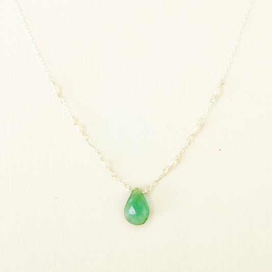 the sea salt necklace by mermaids and madeleines is a pendant style necklace with a teal grandidierite briolette at the center and tiny seed pearls on each side of the sterling chain. this necklace is photographed close up on a white surface